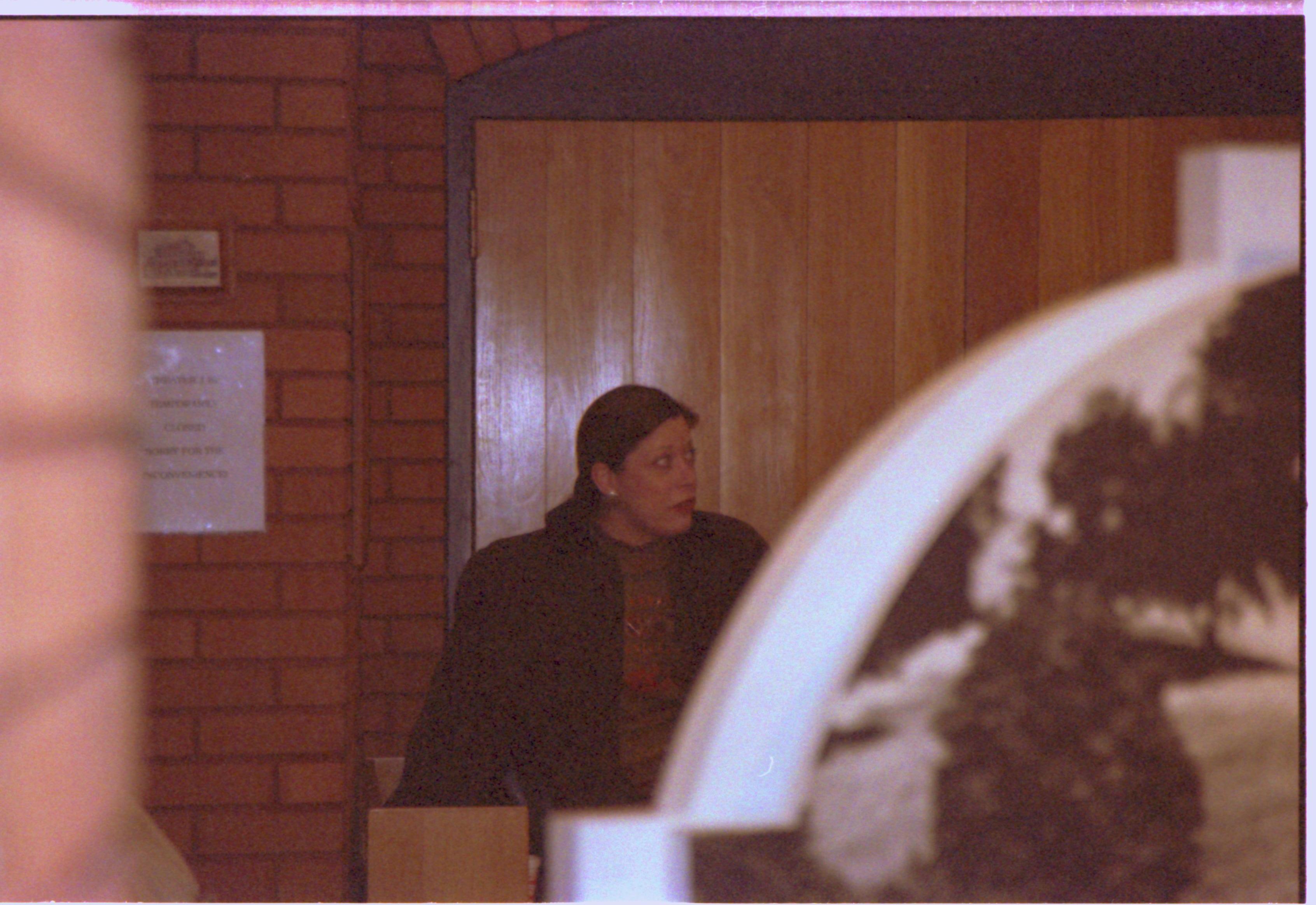 Lady standing in front of theater door. 2-1997 Colloq (color); 6 Colloquium, 1997