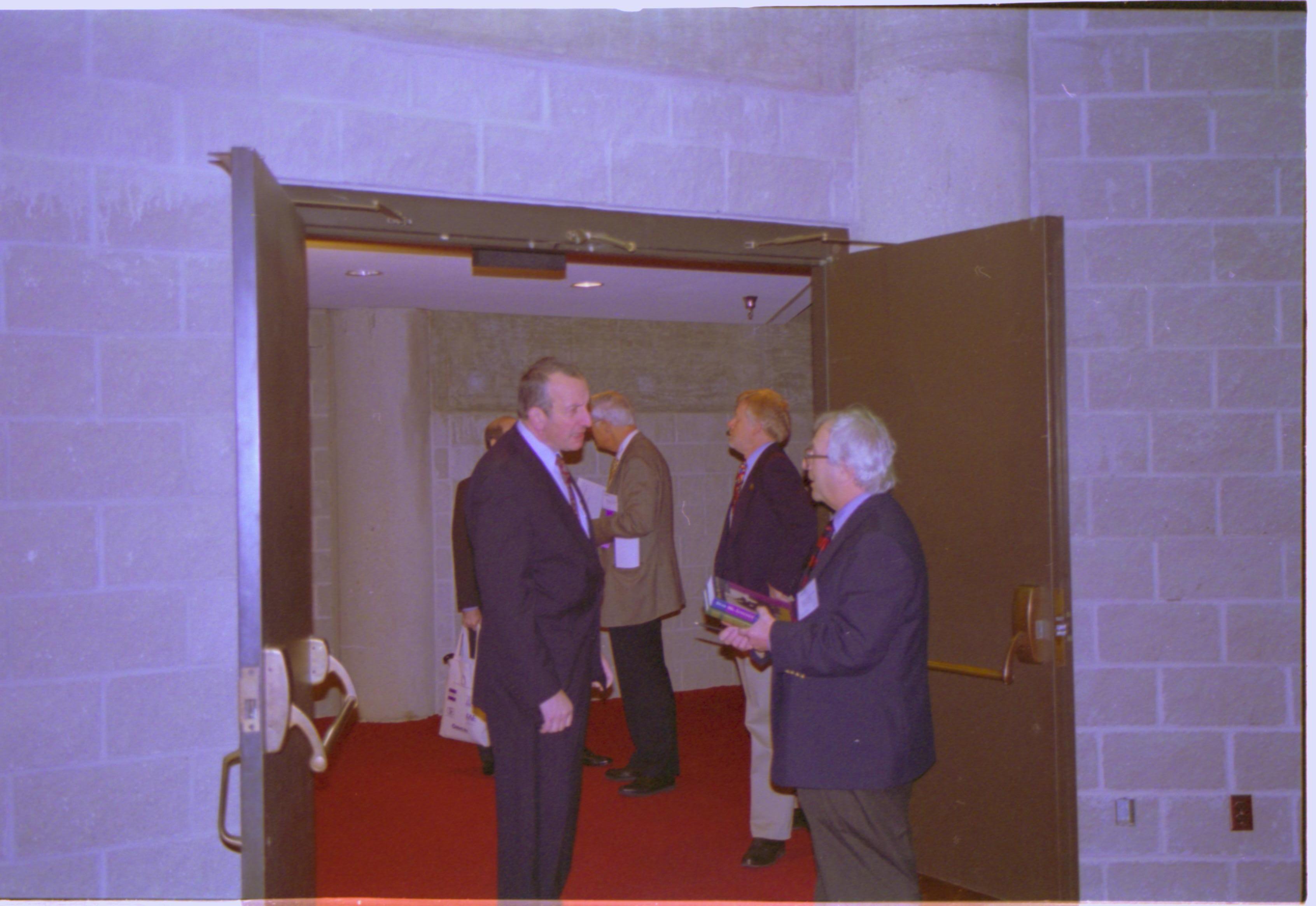 Two men standing in doorway talking. 3-1997 Colloq (color); 4 Colloquium, 1997