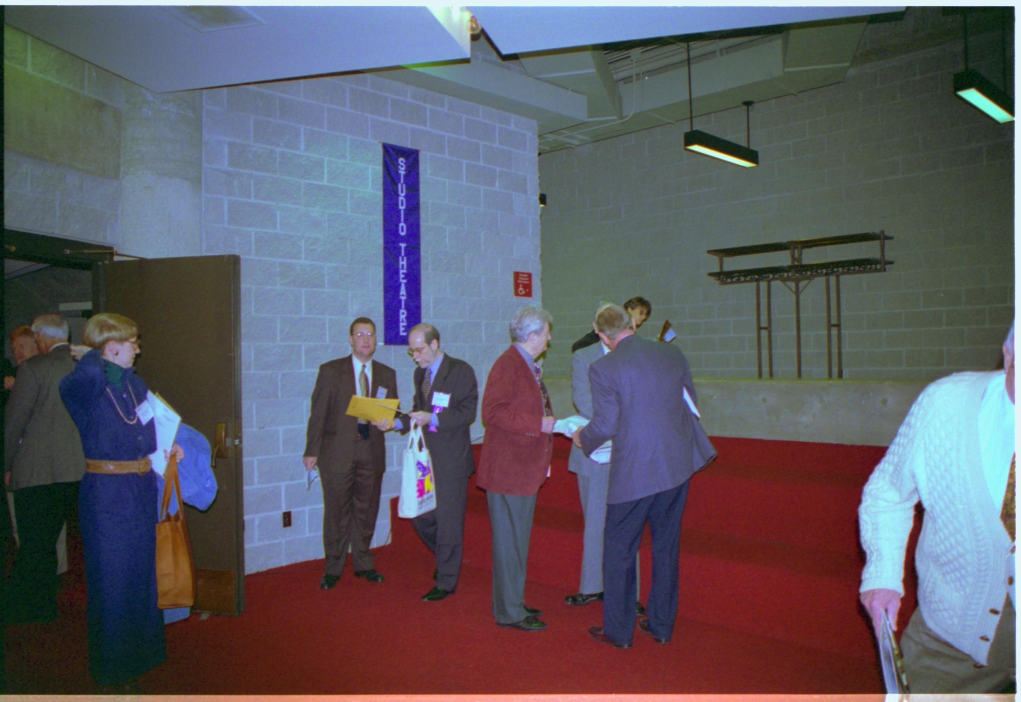 Group of men standing outside theater door. 3-1997 Colloq (color); 9 Colloquium, 1997