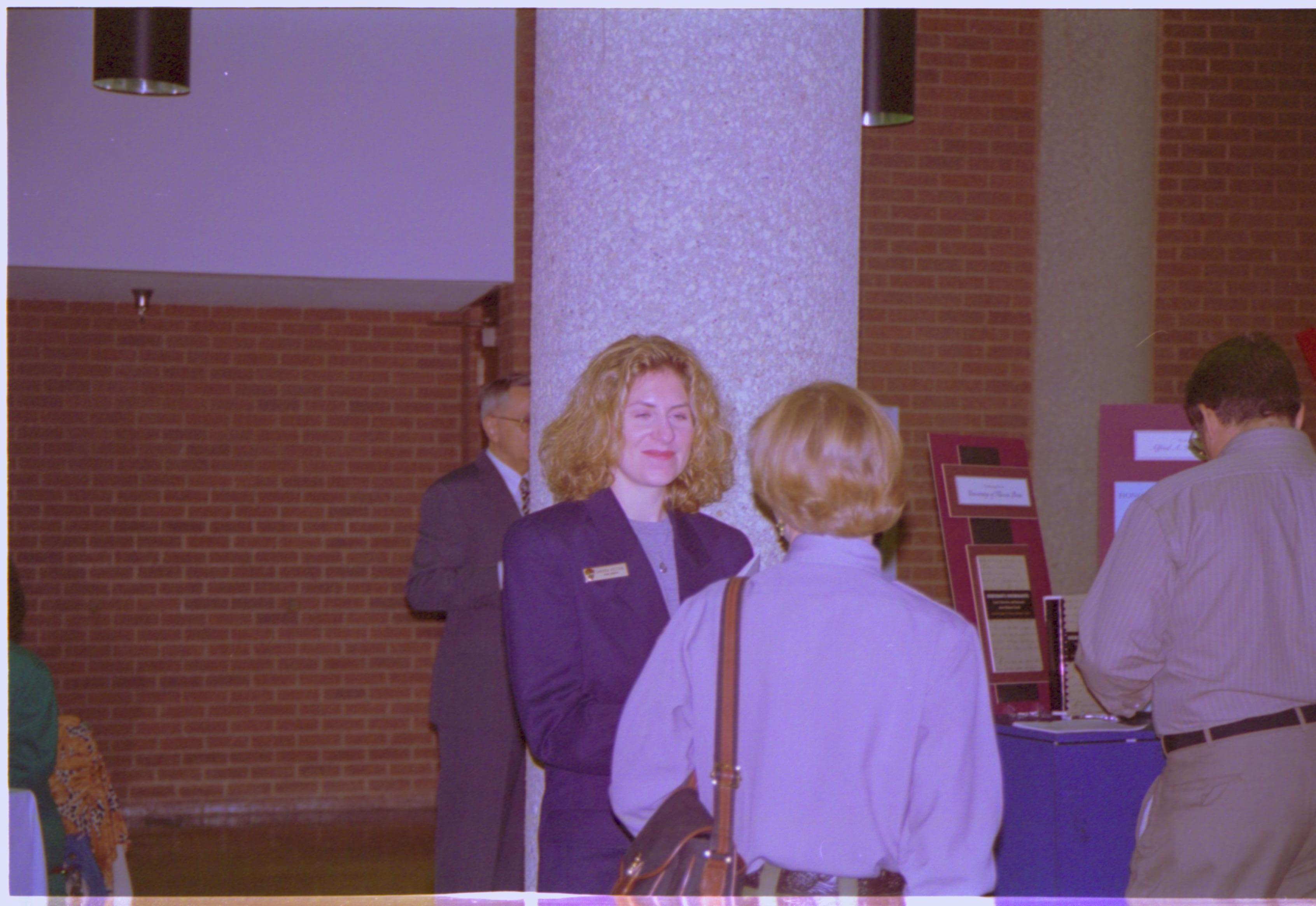 Two ladies talking, man looking at books. 3-1997 Colloq (color); 19 Colloquium, 1997