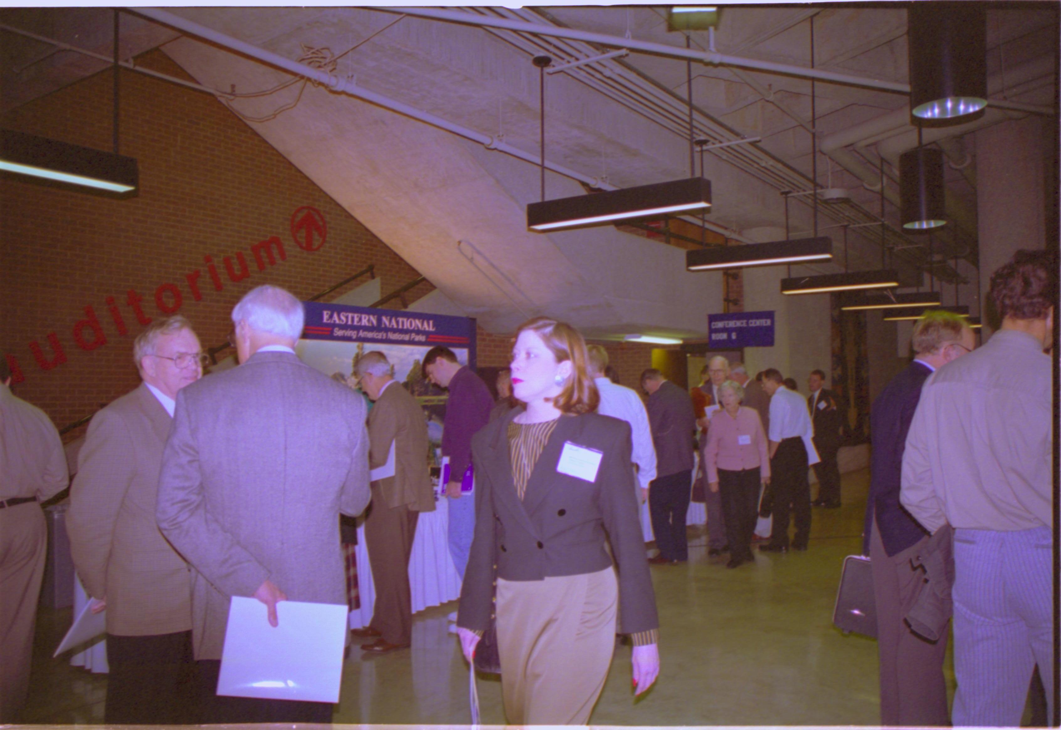 Lady walking in exhibit hall 3-1997 Colloq (color); 20 Colloquium, 1997