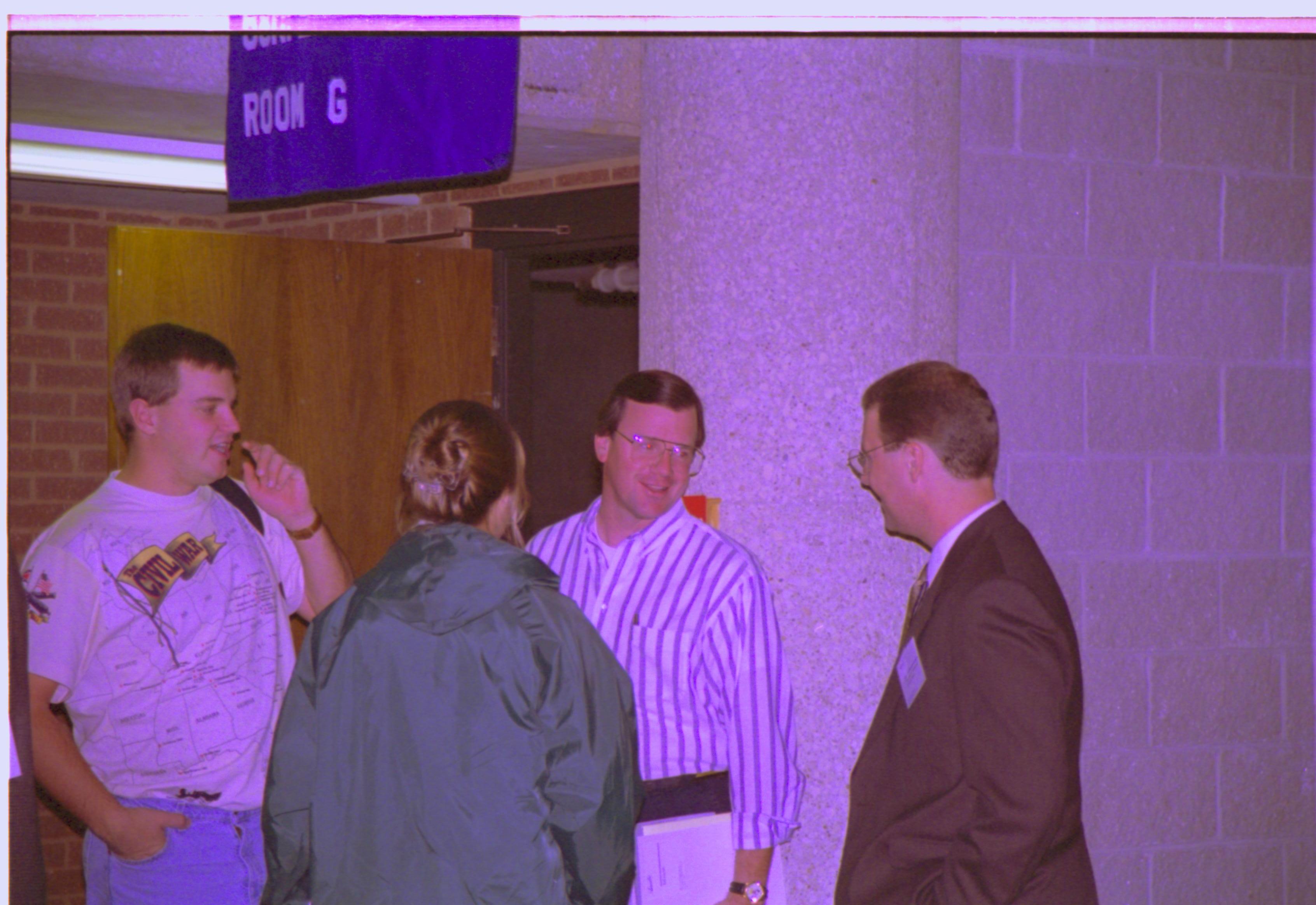 Three men and a lady standing, talking. 3-1997 Colloq (color); 23 Colloquium, 1997