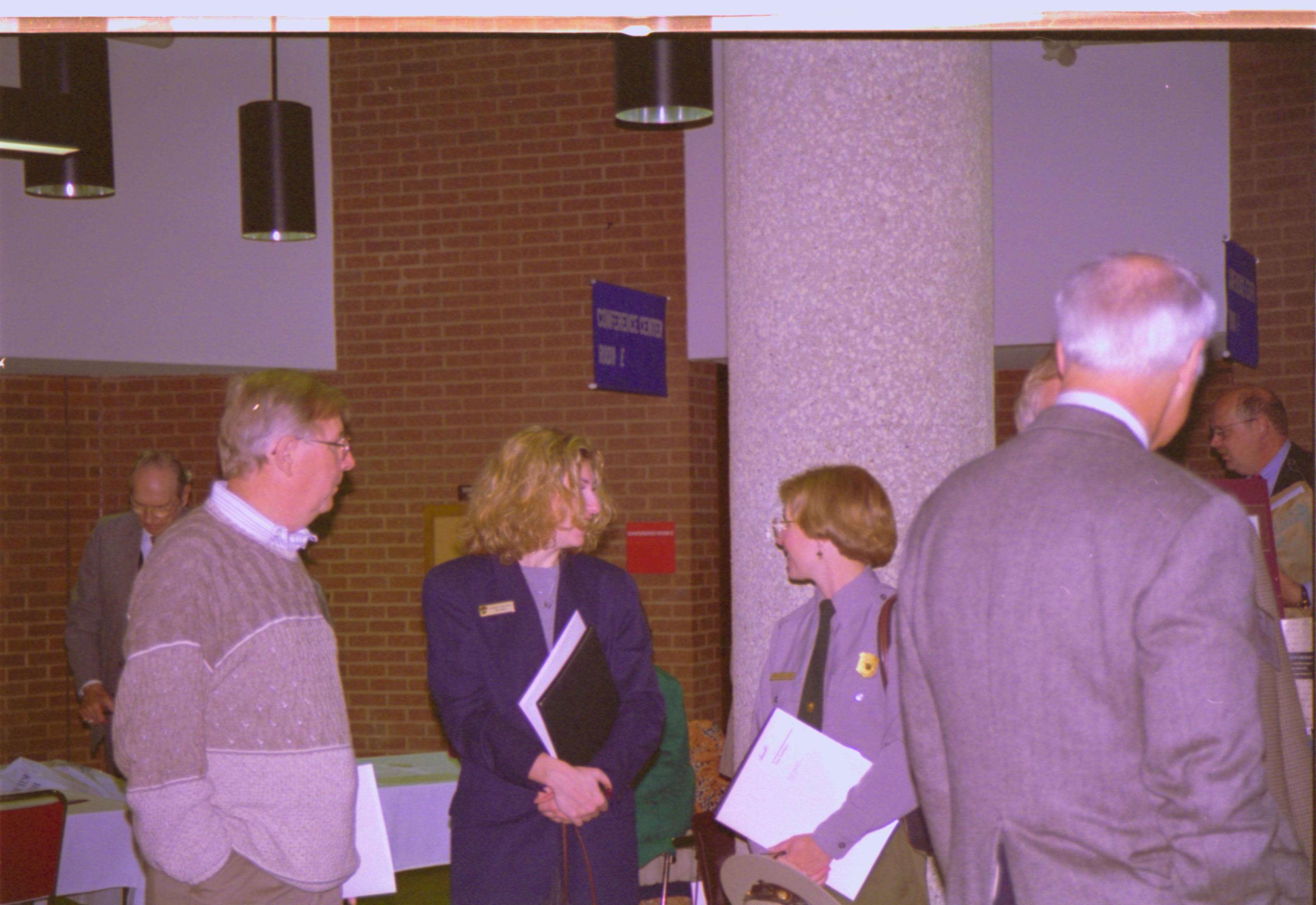 Ranger talking with man and woman in exhibit hall. 3-1997 Colloq (color); 24 Colloquium, 1997