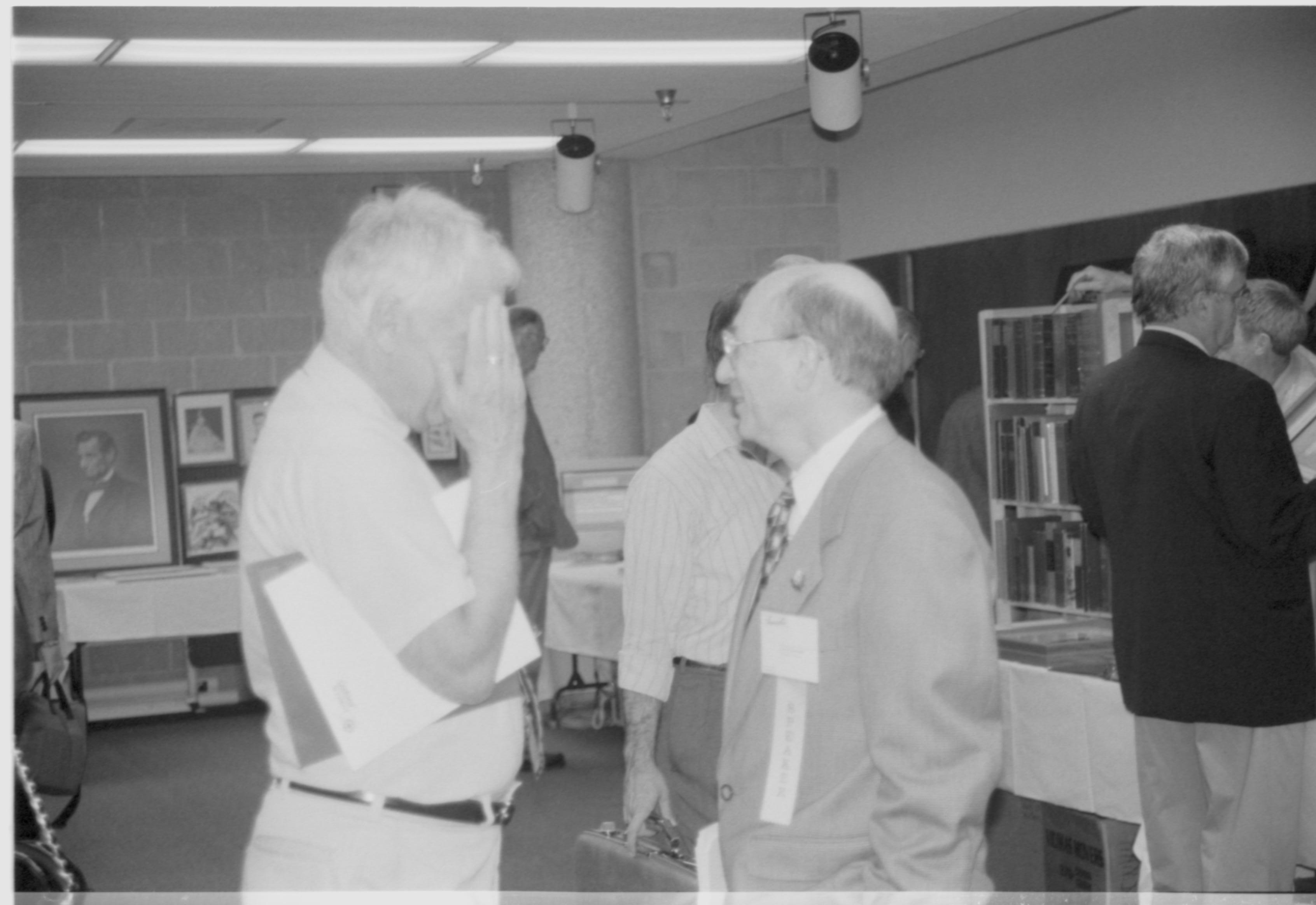 Two men in exhibit area talking. 1999-16; 13 Colloquium, 1999