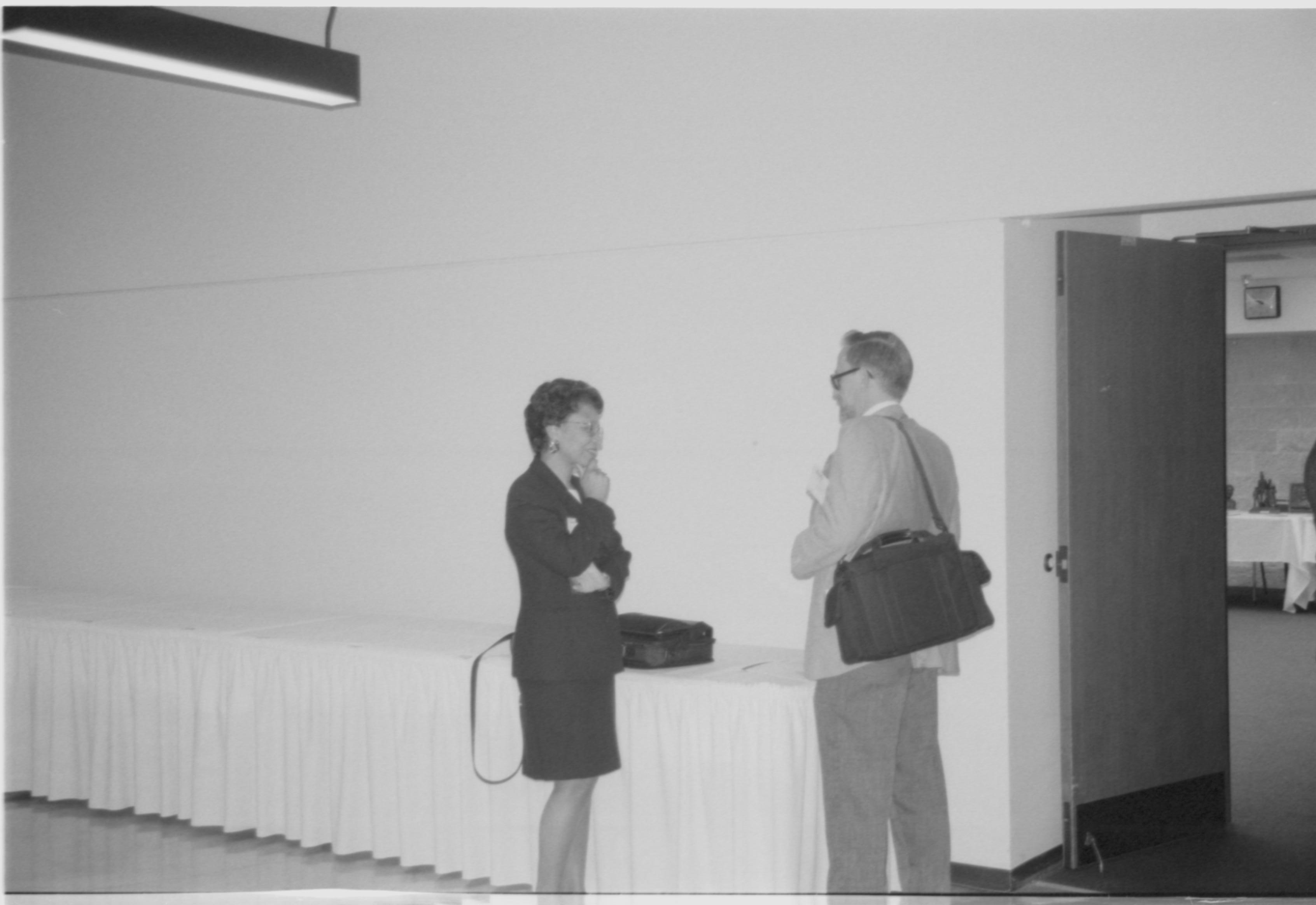 Lady speaking with man in front of curtain. 1999-16; 14 Colloquium, 1999