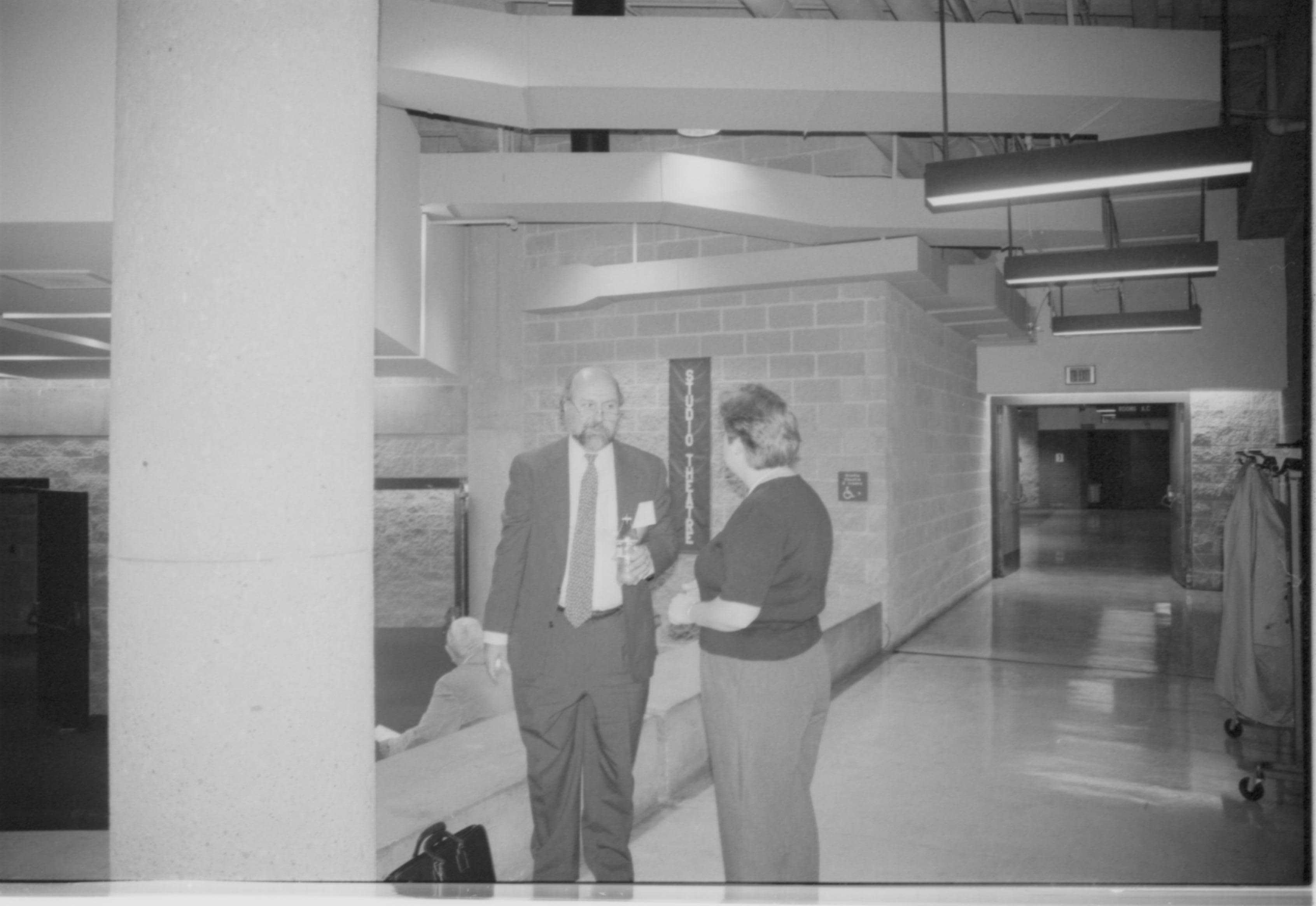 Man and lady standing, talking in hallway. 1999-16; 15 Colloquium, 1999