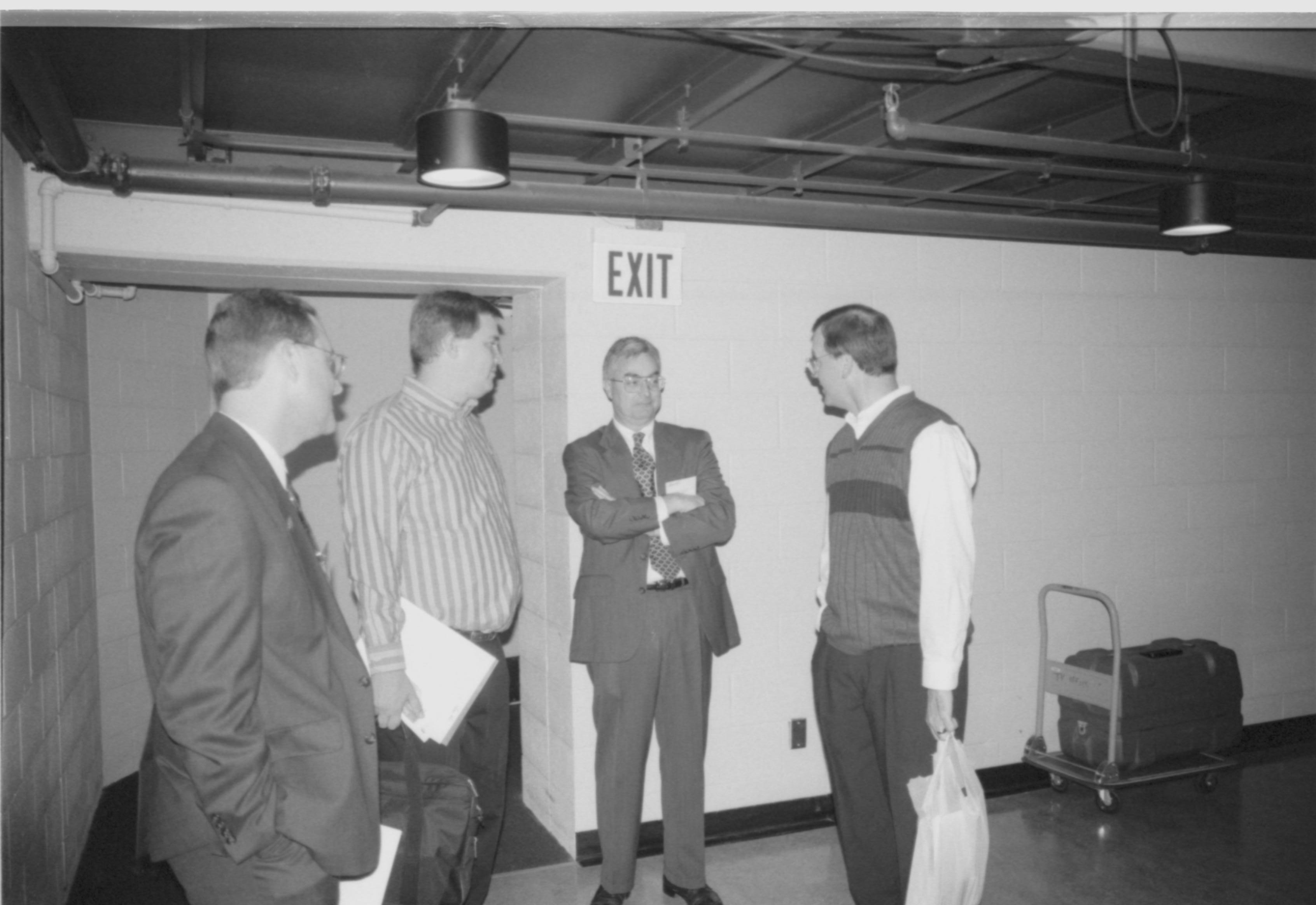 Four men standing, talking. 1999-16; 16 Colloquium, 1999