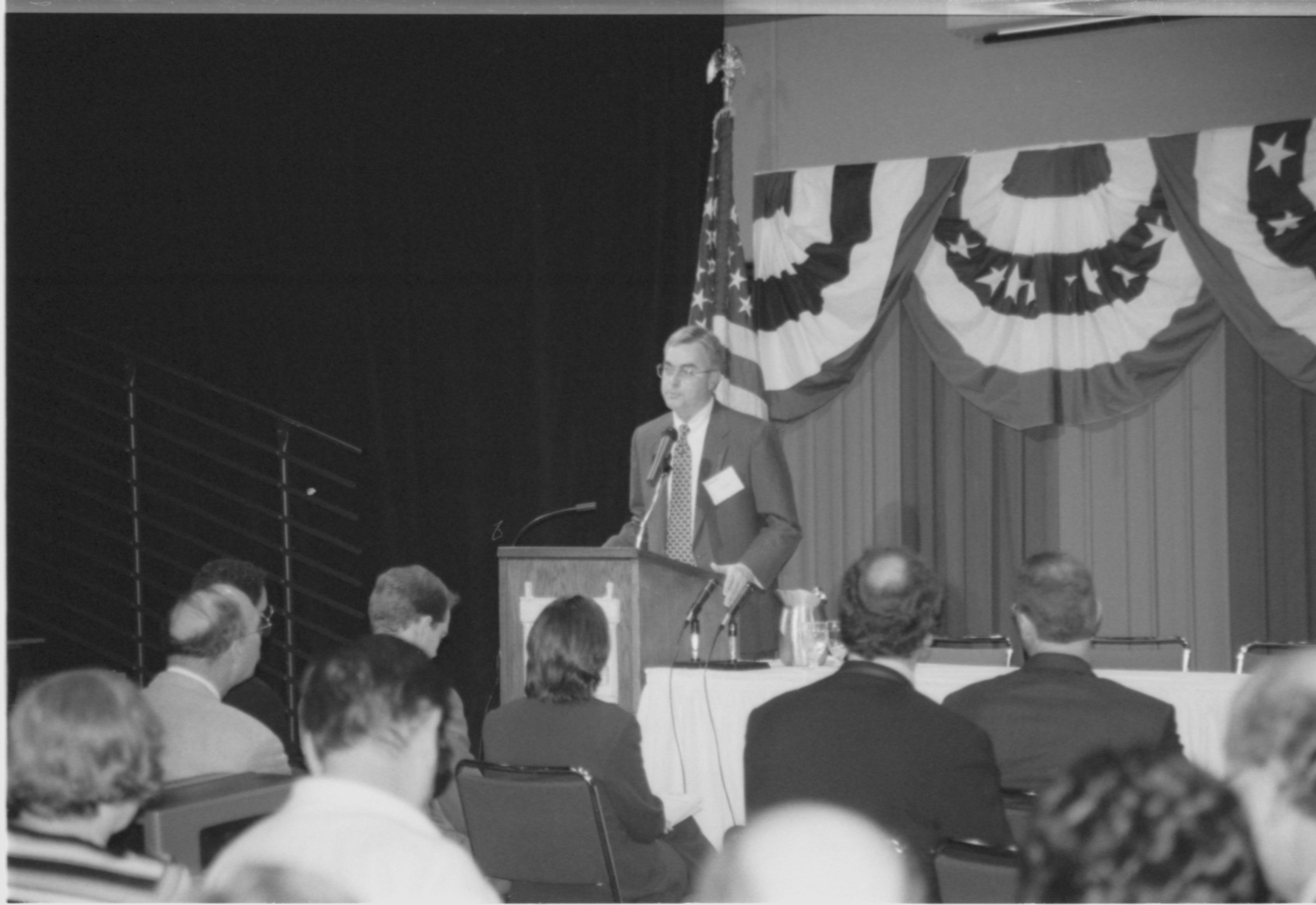 Speaker at podium, audience close by. 1999-16; 17 Colloquium, 1999