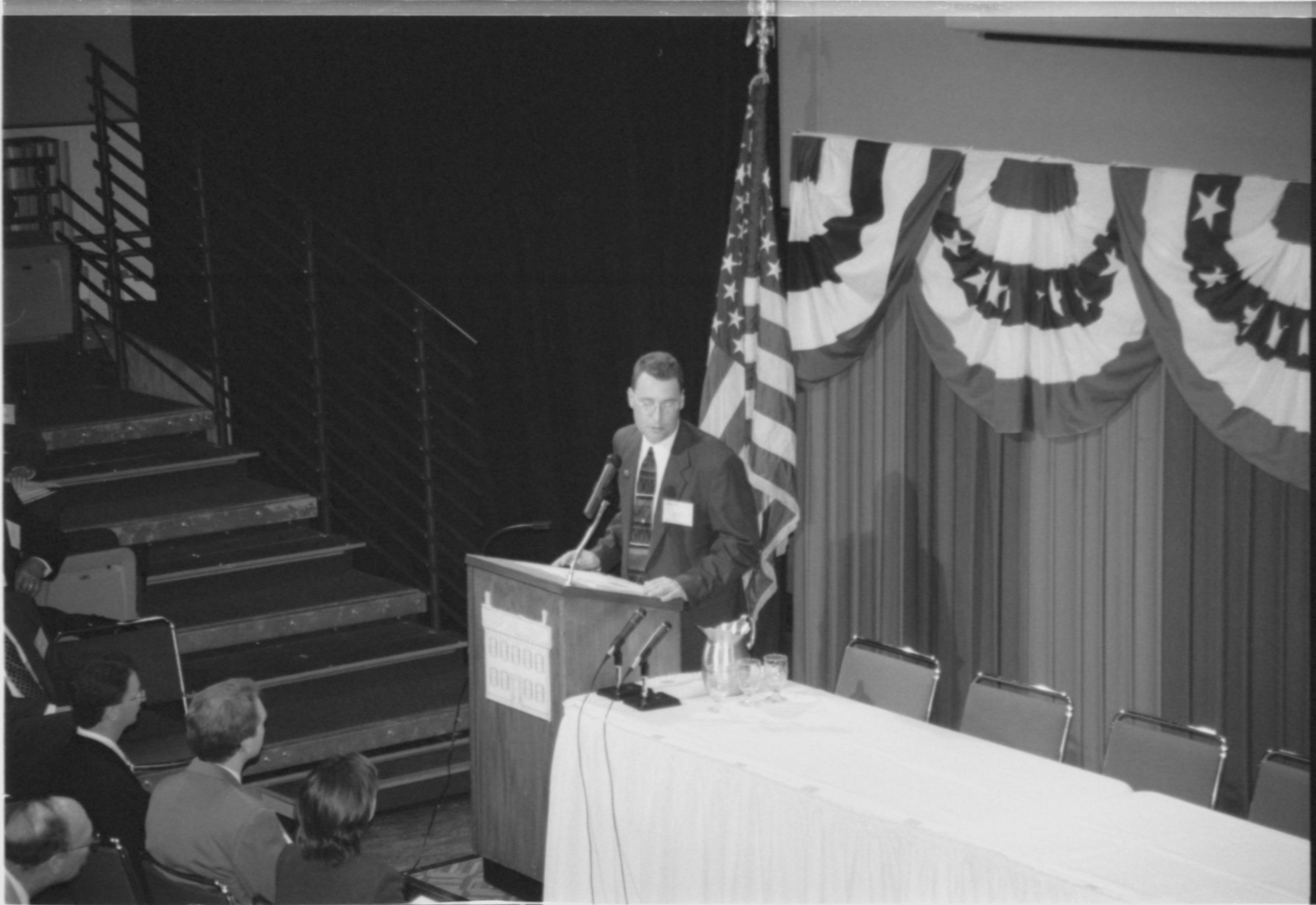 Man at podium, audience close by. 1999-16; 19 Colloquium, 1999