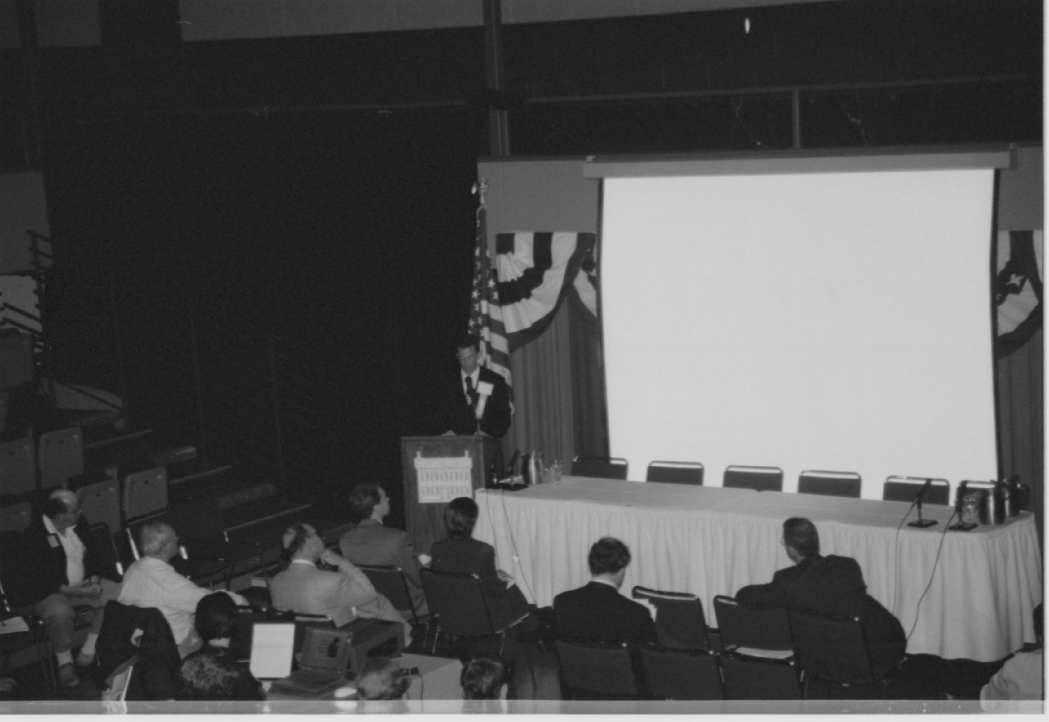 Male speaker, screen in background.  1999-16; 23 Colloquium, 1999