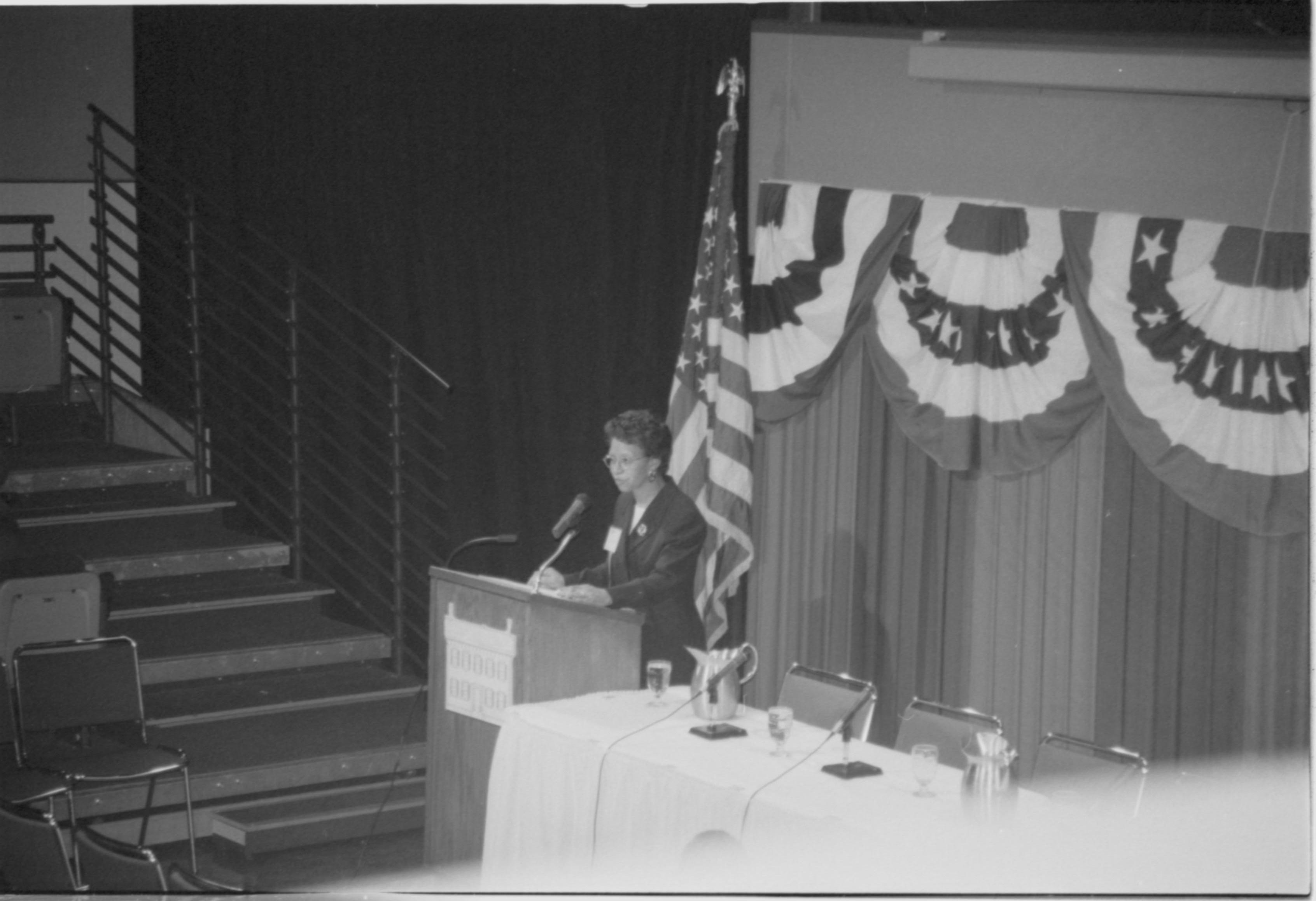 Lady speaking at podium. 1999-16; 35 Colloquium, 1999