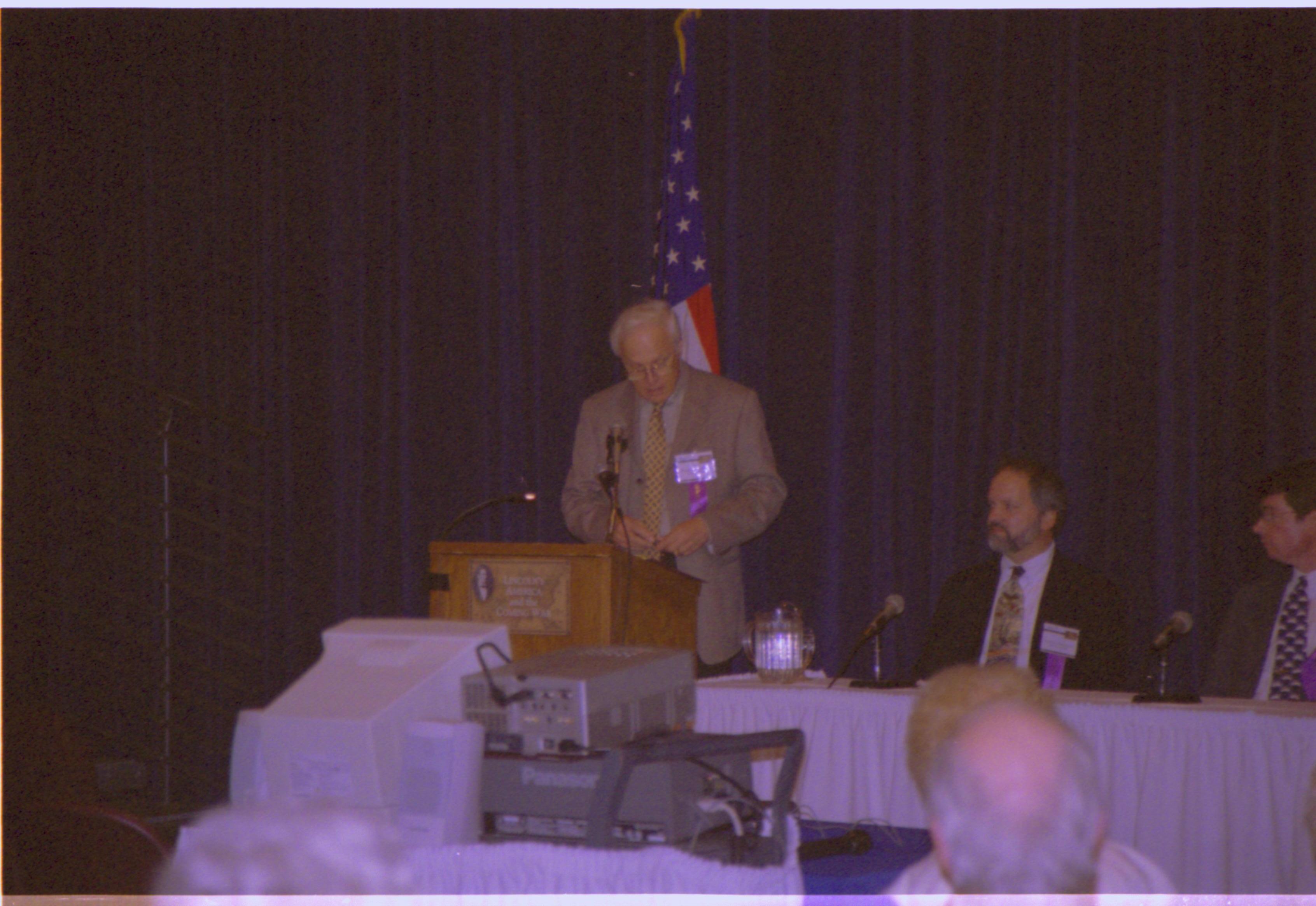 Speaker at podium (yellow tie). Colloquium, 2001