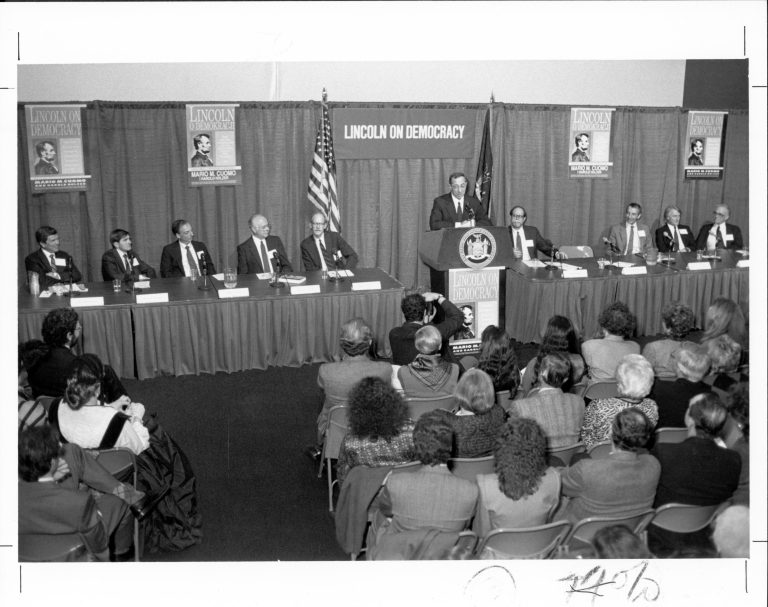 1990 Booklet-9 men seated on platform, another speaking-Lincoln on Democracy Lincoln, Colloquium