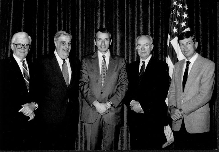 Five men posing for picture by American flag. Lincoln, Colloquium
