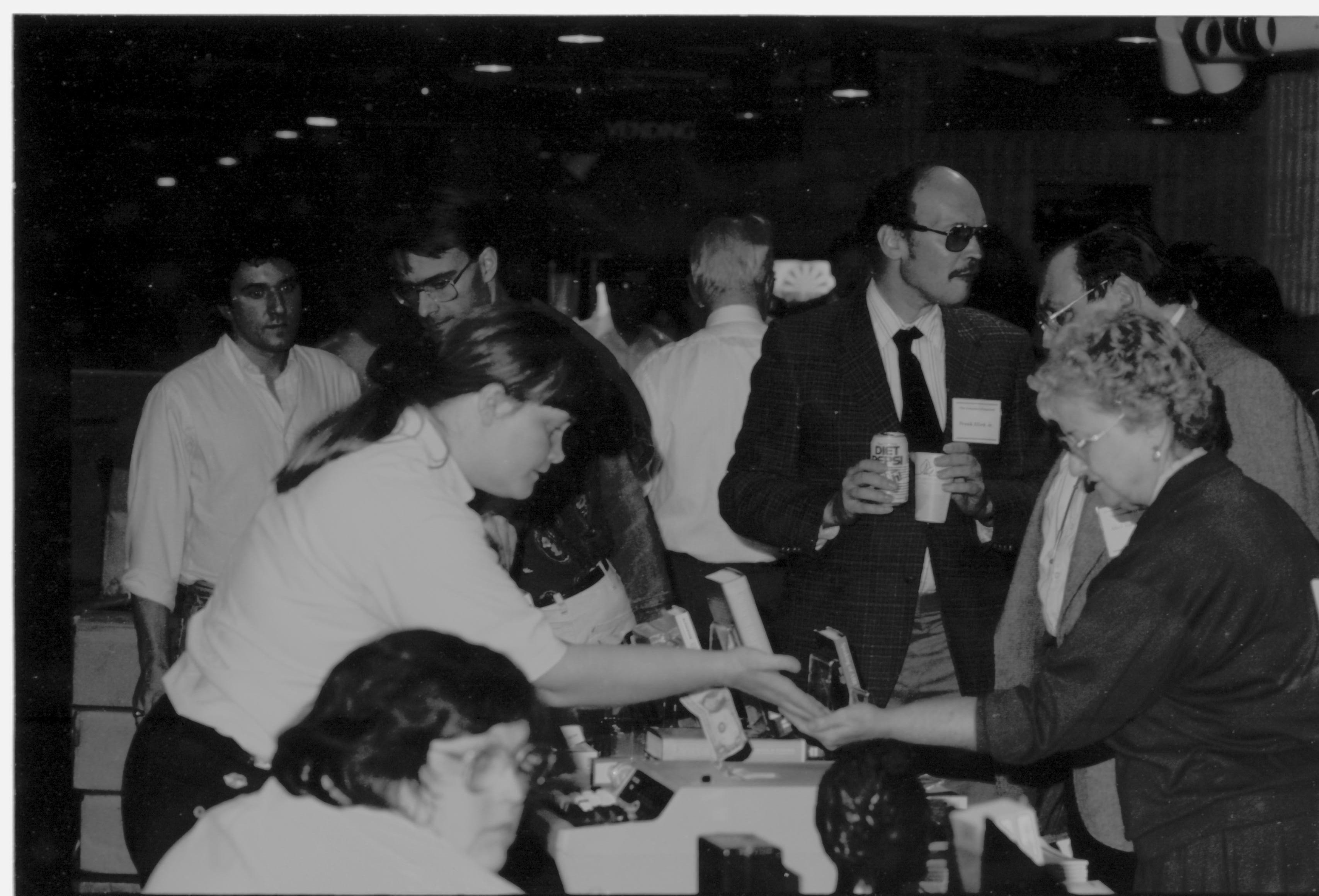 Visitors buying books and talking. Colloquium, 1991 Lincoln, Colloquium