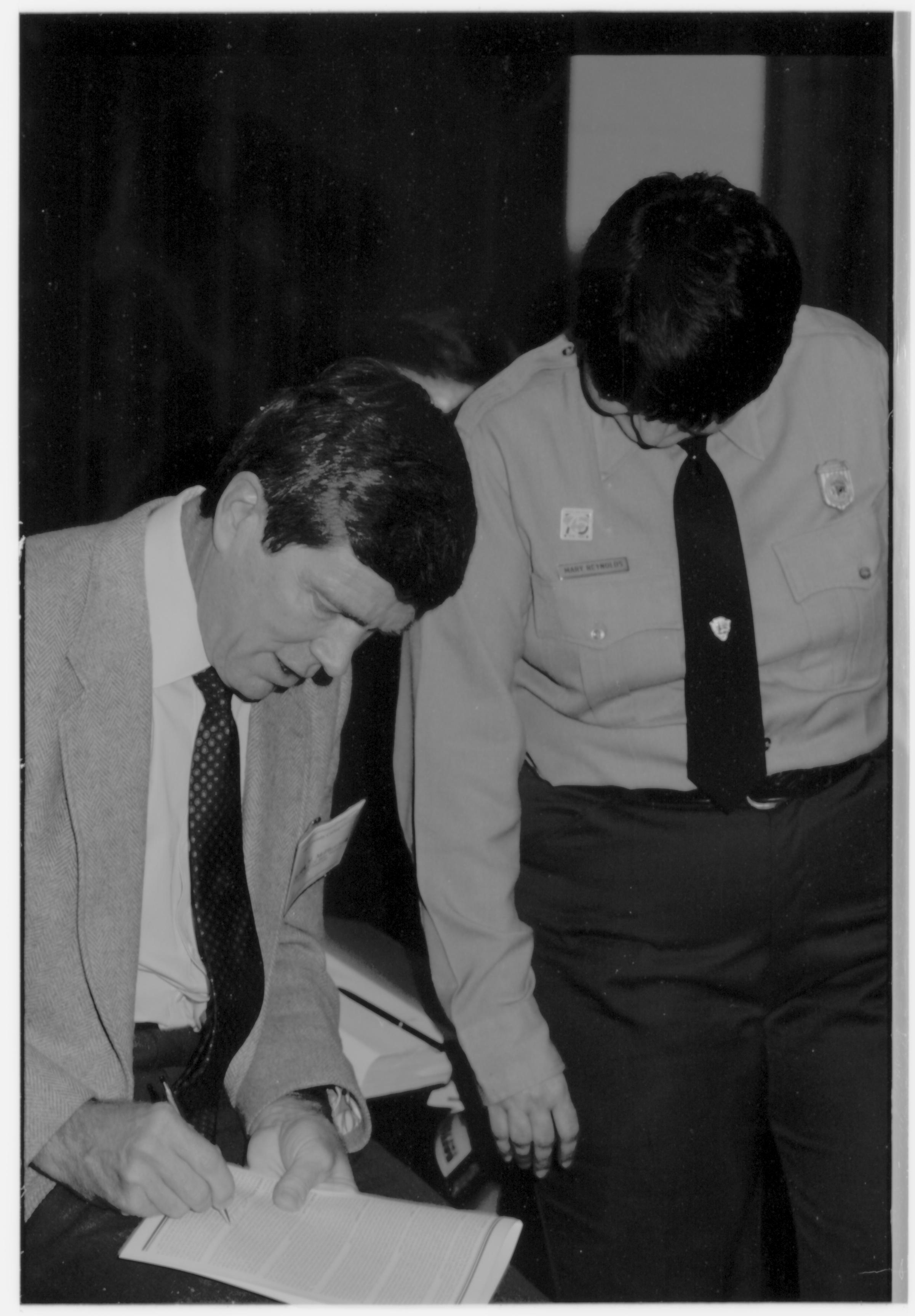 Man signing booklet. Colloquium, 1991 Lincoln, Colloquium