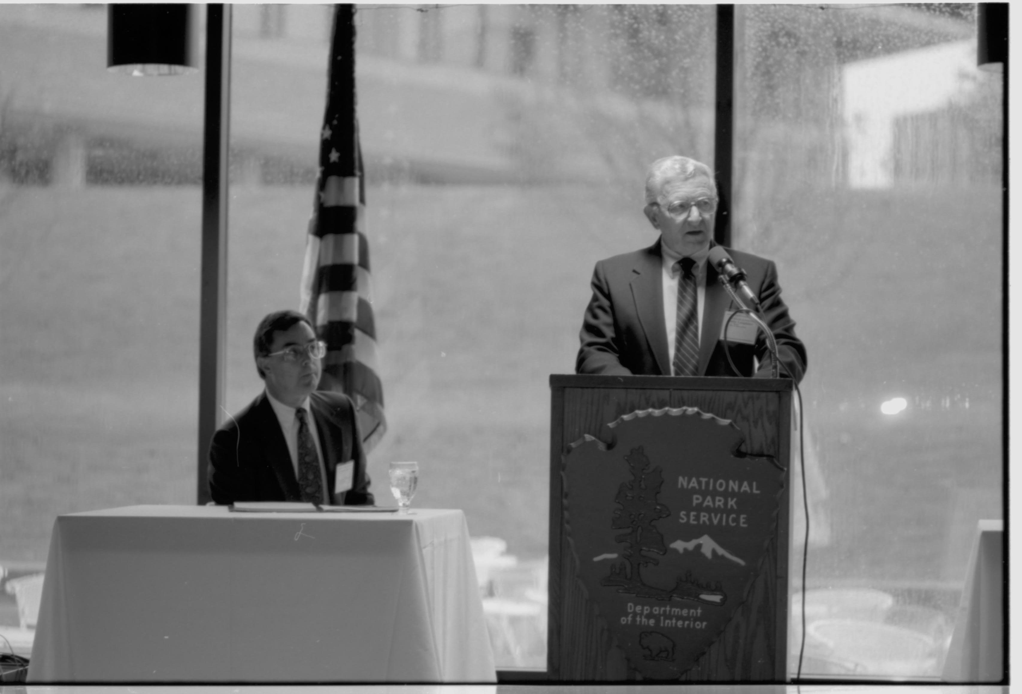 One man seated, one standing speaking. Colloquium, 1991 Lincoln, Colloquium