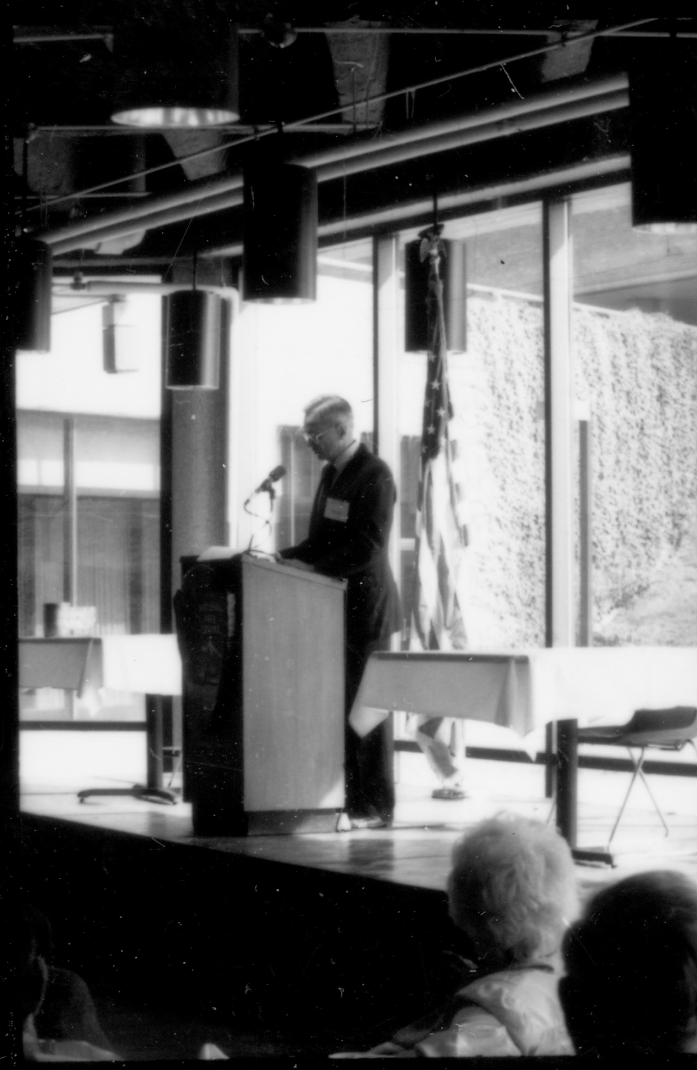 Man speaking at podium, glass windows behind. 1992 Lincoln Colloquium Lincoln, Colloquium