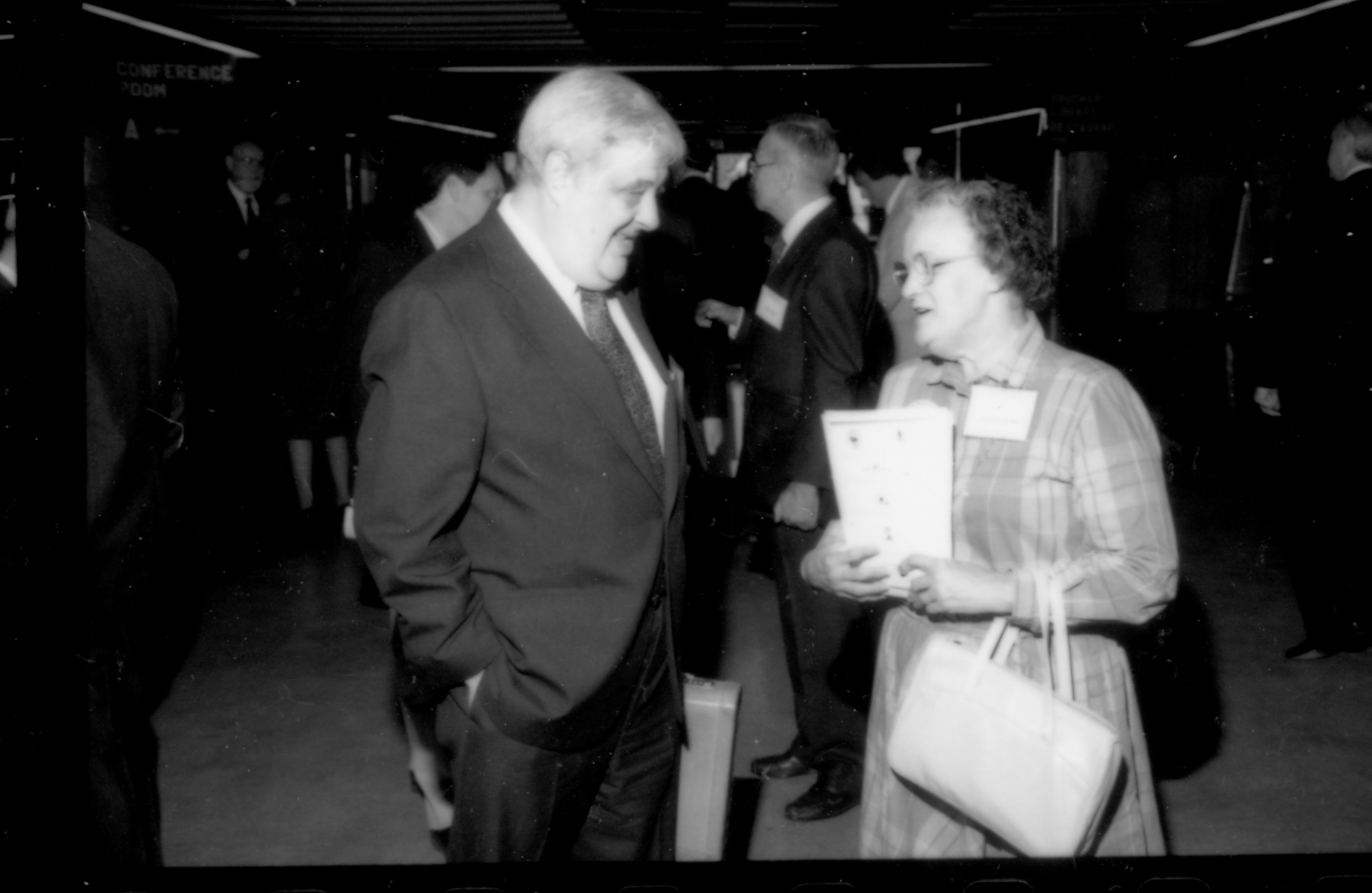 Lady with booklet talking to man. 1992 Lincoln Colloquium; Outside #72 Lincoln, Colloquium