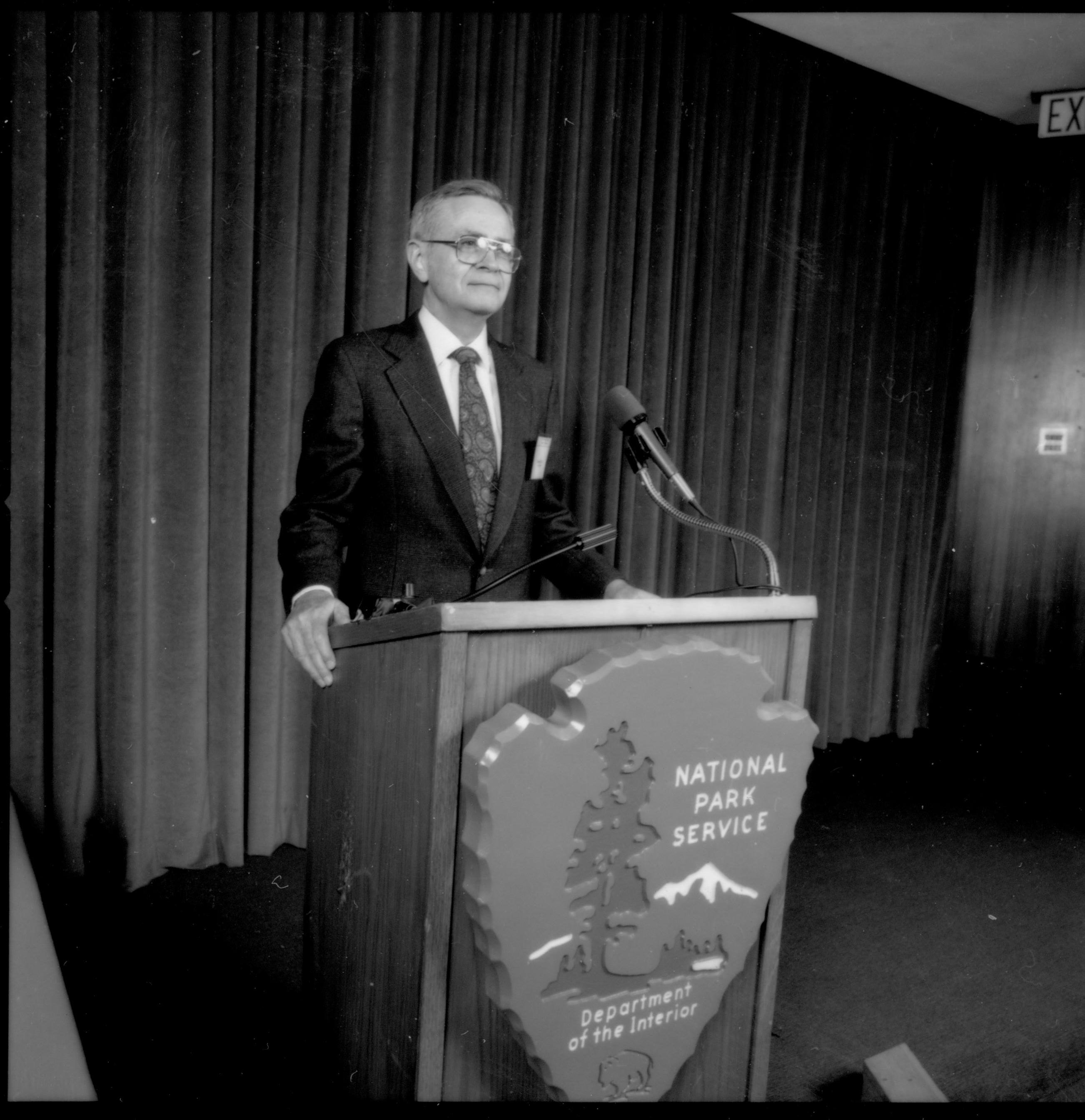 Man at podium with curtain behind him. 1992 Lincoln Colloquium; Outside #69 Lincoln, Colloquium