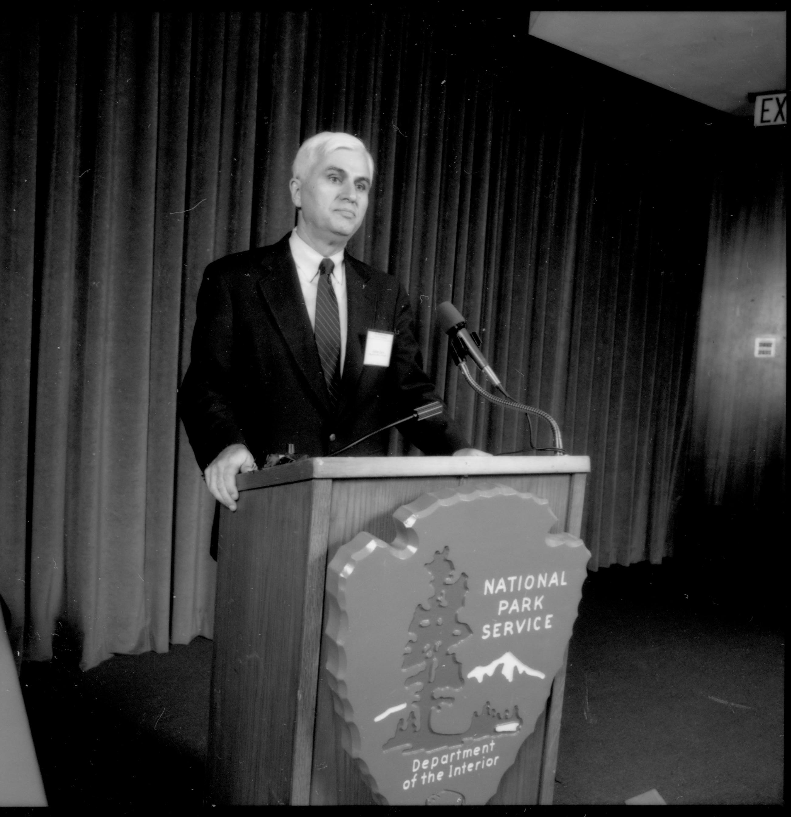 Man at podium with curtain behind him. 1992 Lincoln Colloquium; Outside #69 Lincoln, Colloquium