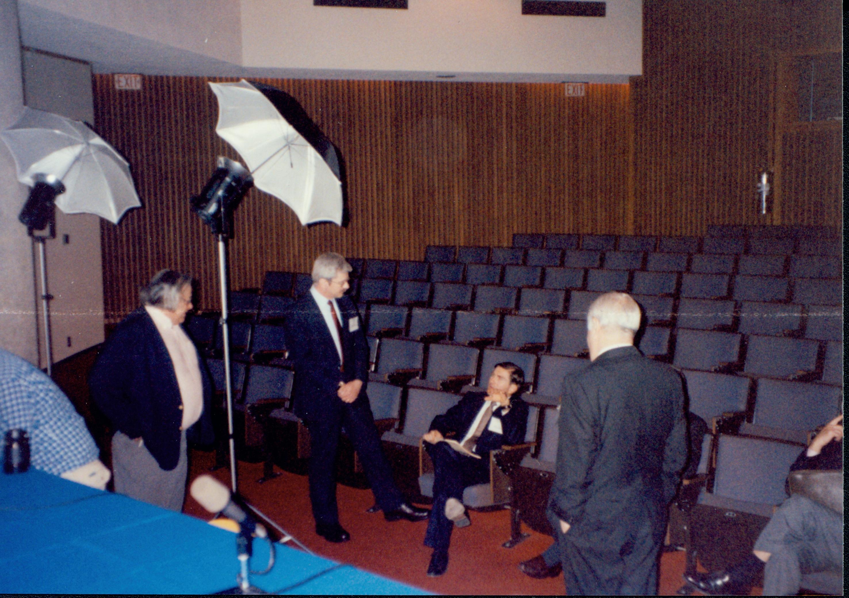 Three man standing, one sitting in empty auditorum. 1992 Lincoln Colloquium Lincoln, Colloquium