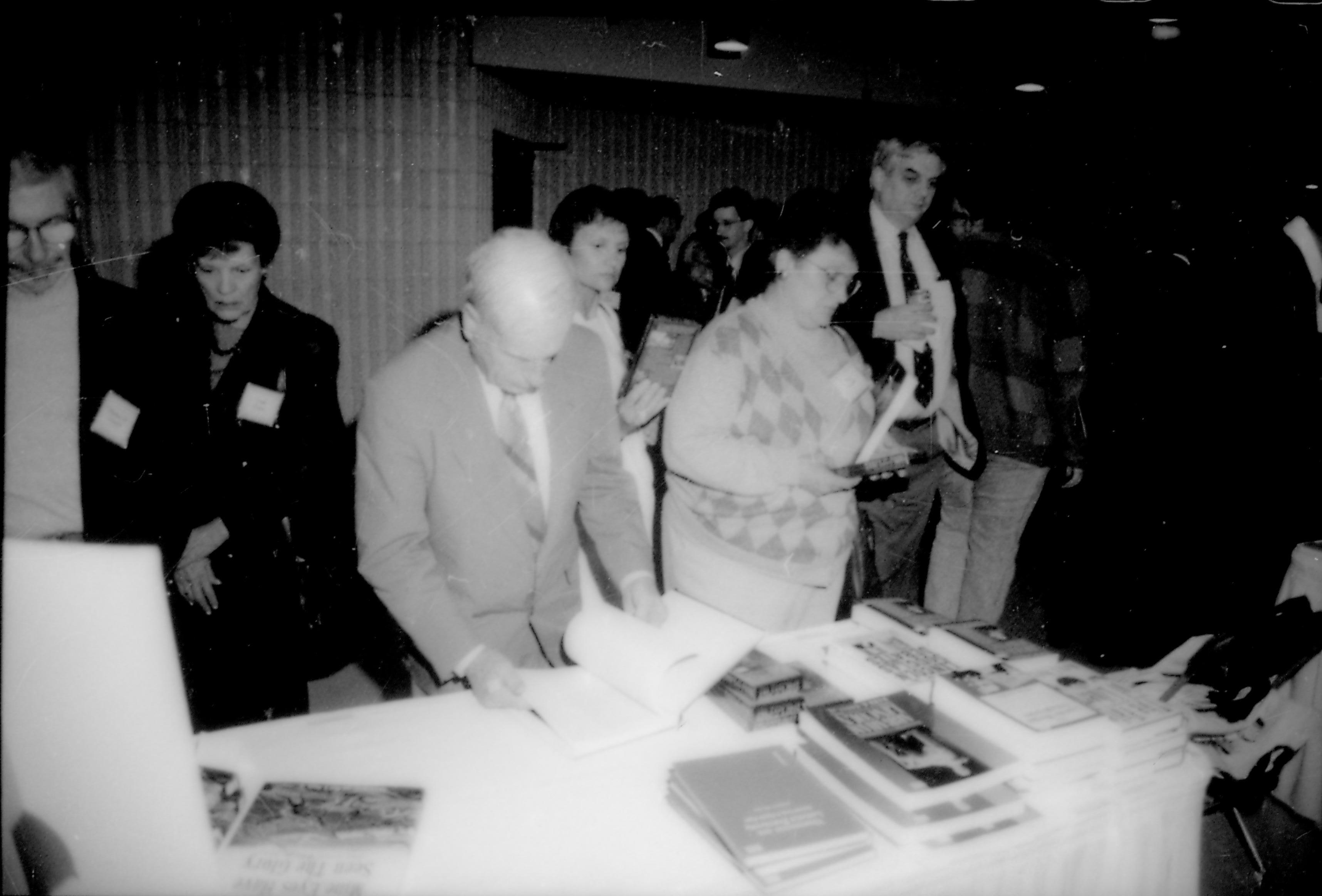 People looking at books at book table. 8th Annual Lincoln Colloquium; E Lincoln, Colloquium