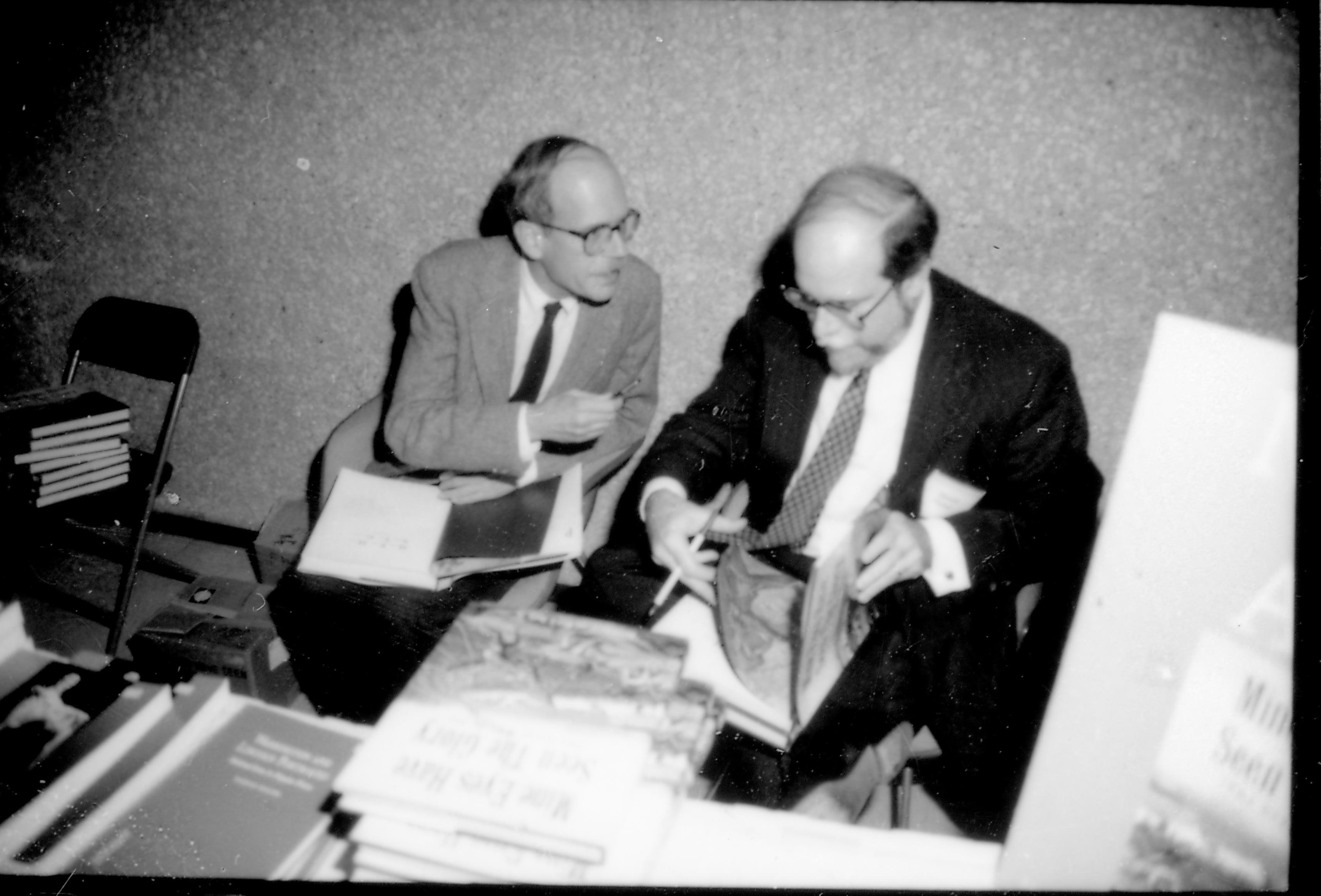 Two men seated behind book table. 8th Annual Lincoln Colloquium; E Lincoln, Colloquium