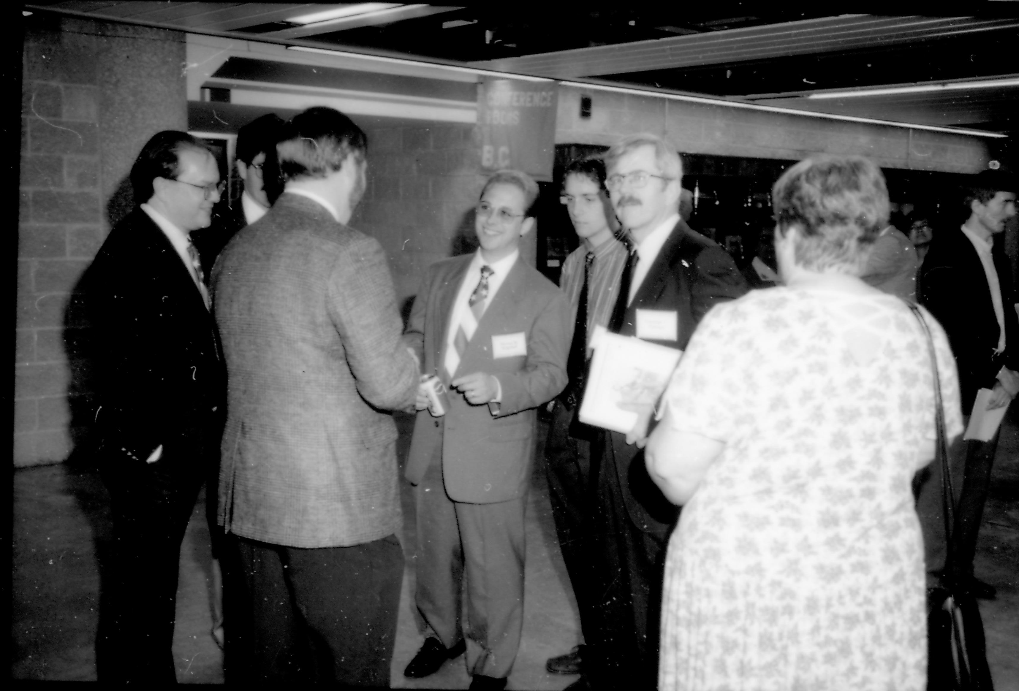 Group of men (one woman) standing, talking. 8th Annual Lincoln Colloquium; A Lincoln, Colloquium