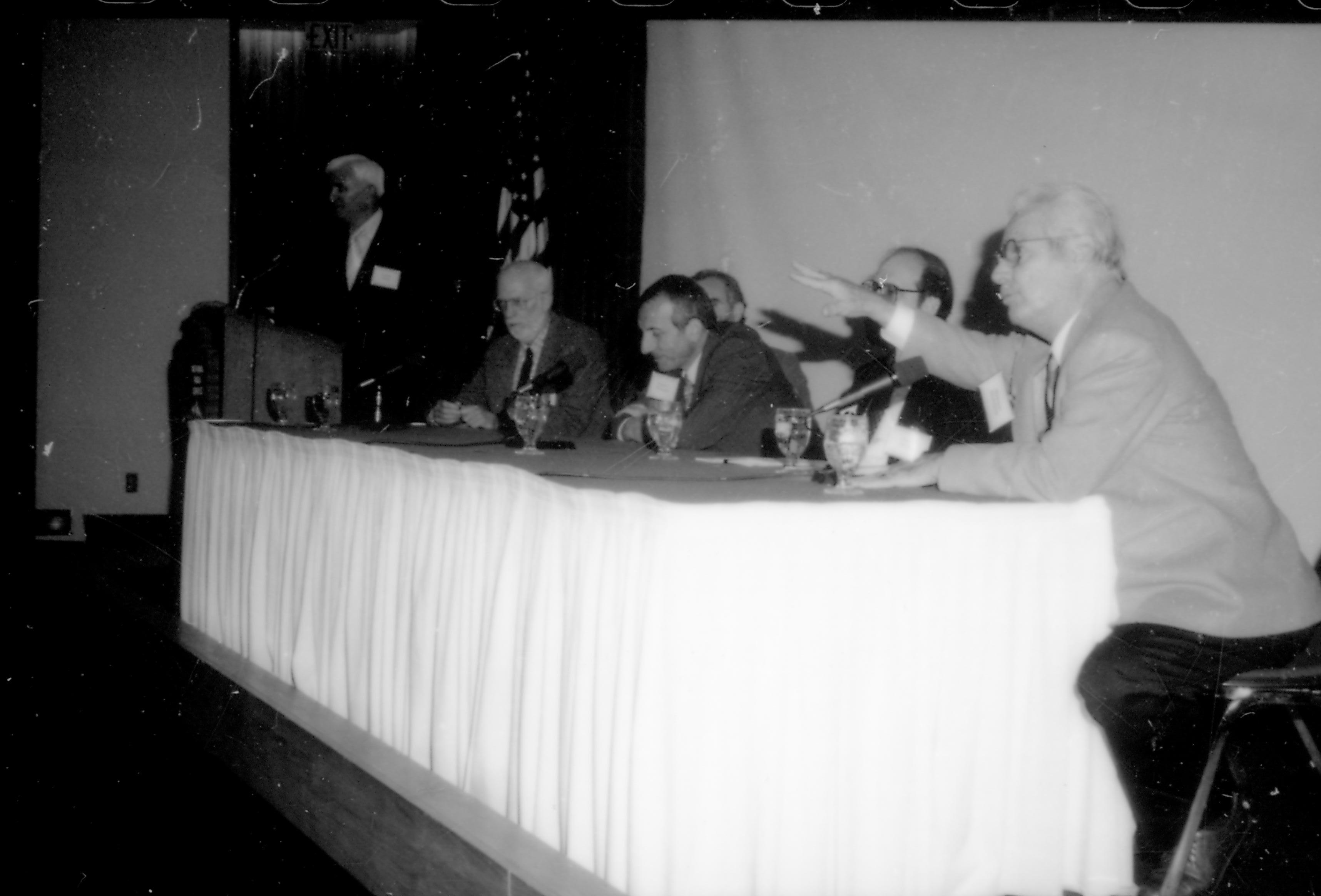 Speakers sitting at table, one at podium. 8th Annual Lincoln Colloquium; E Lincoln, Colloquium