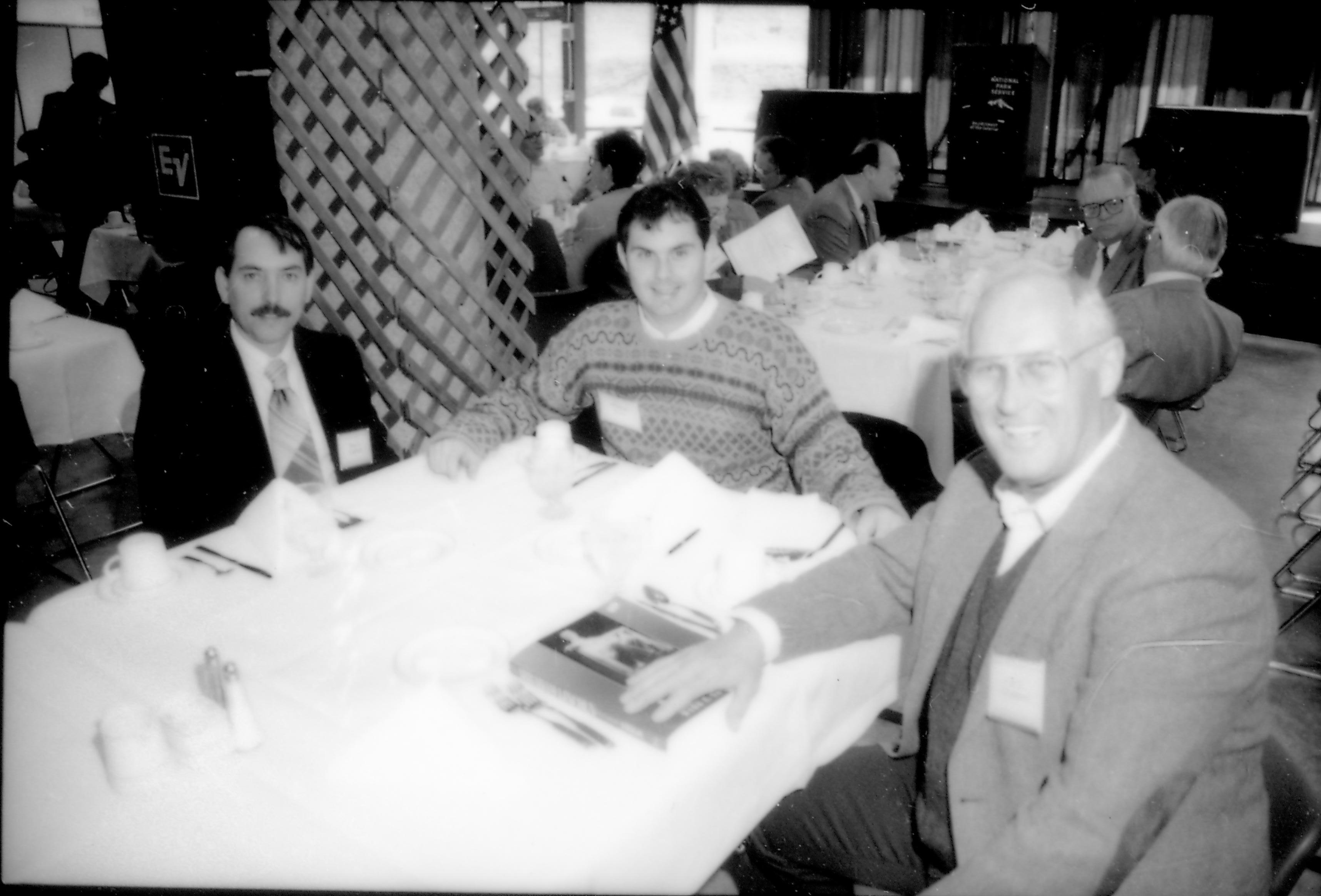 Three men seated at table posing for picture. 8th Annual Lincoln Colloquium; A Lincoln, Colloquium