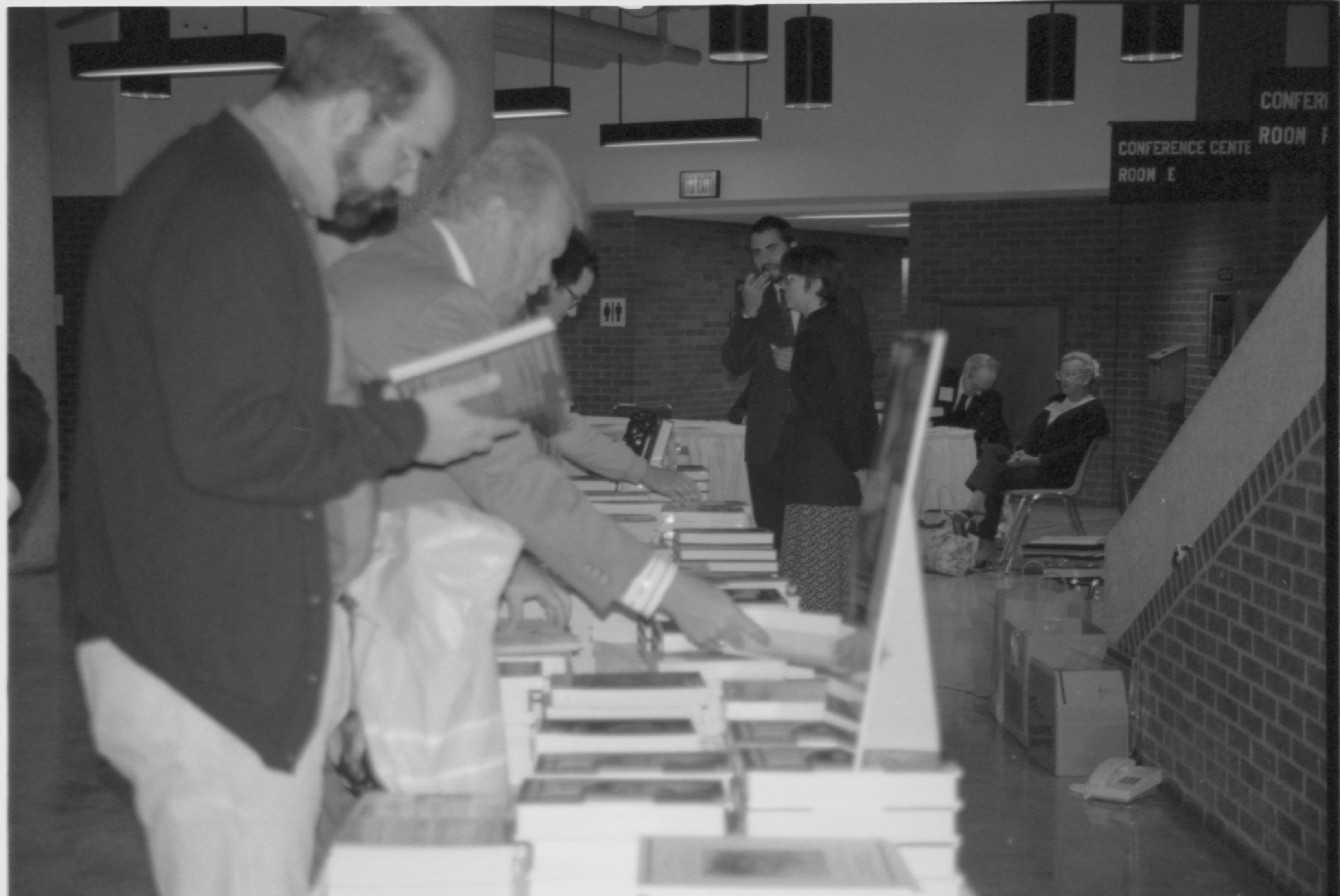 Attendees looking at books on table. Lincoln Colloquium; 88257 Lincoln, Colloquium