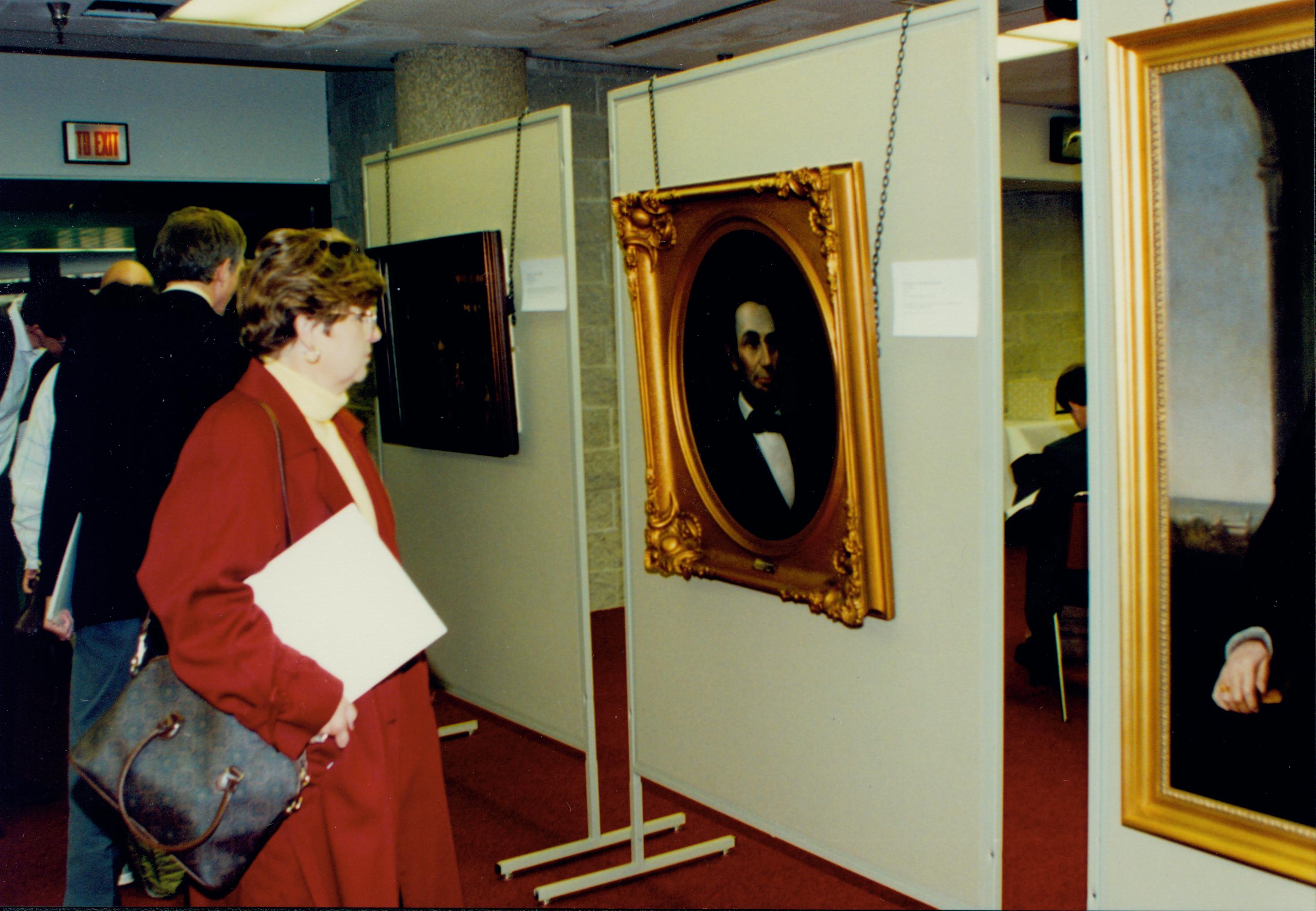 Lady looking at portrait of Lincoln. Lincoln Colloquium; 56945 Lincoln, Colloquium