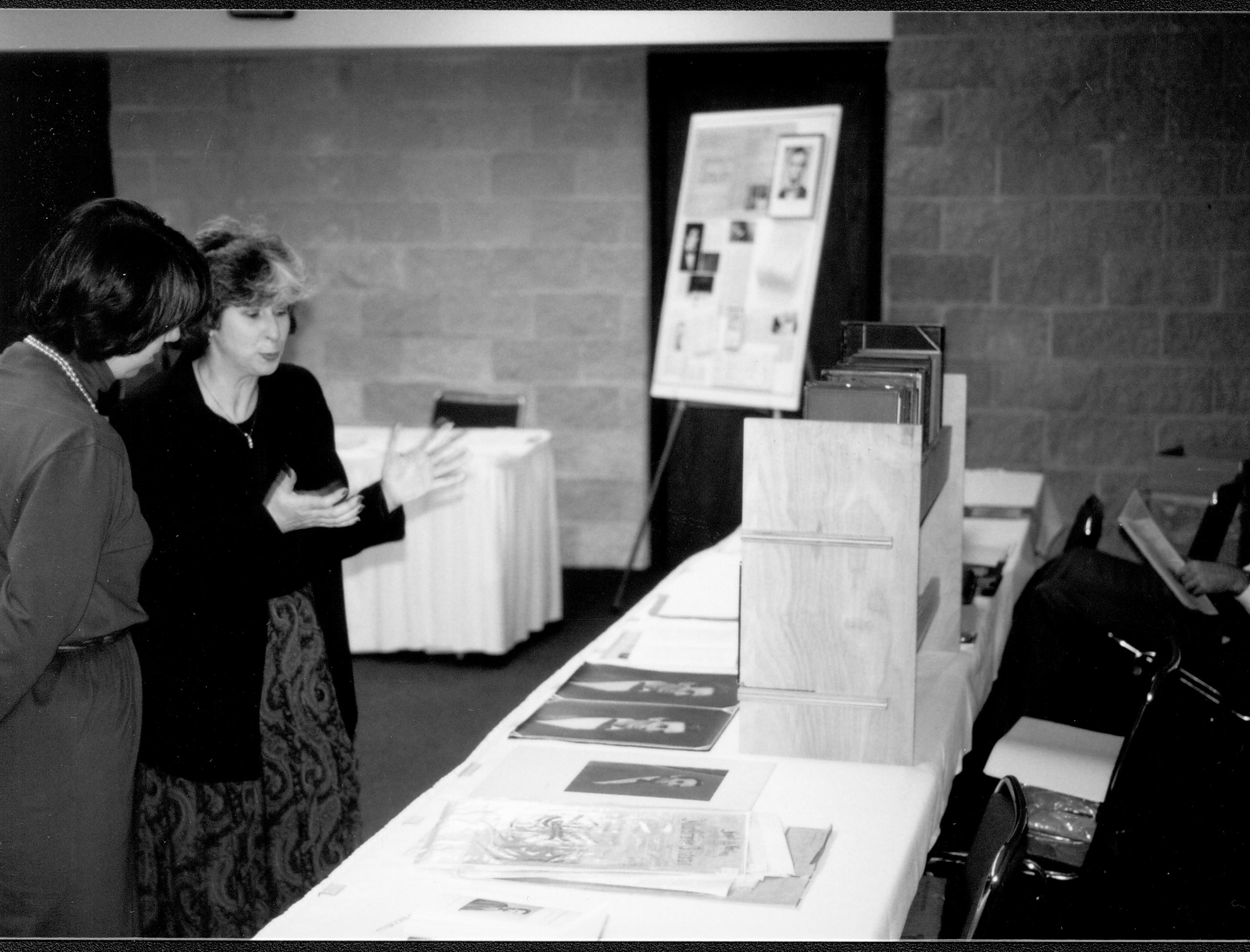Two ladies talking at display table. Lincoln Colloquium; UIS Roll#1, 3of4 Lincoln, Colloquium