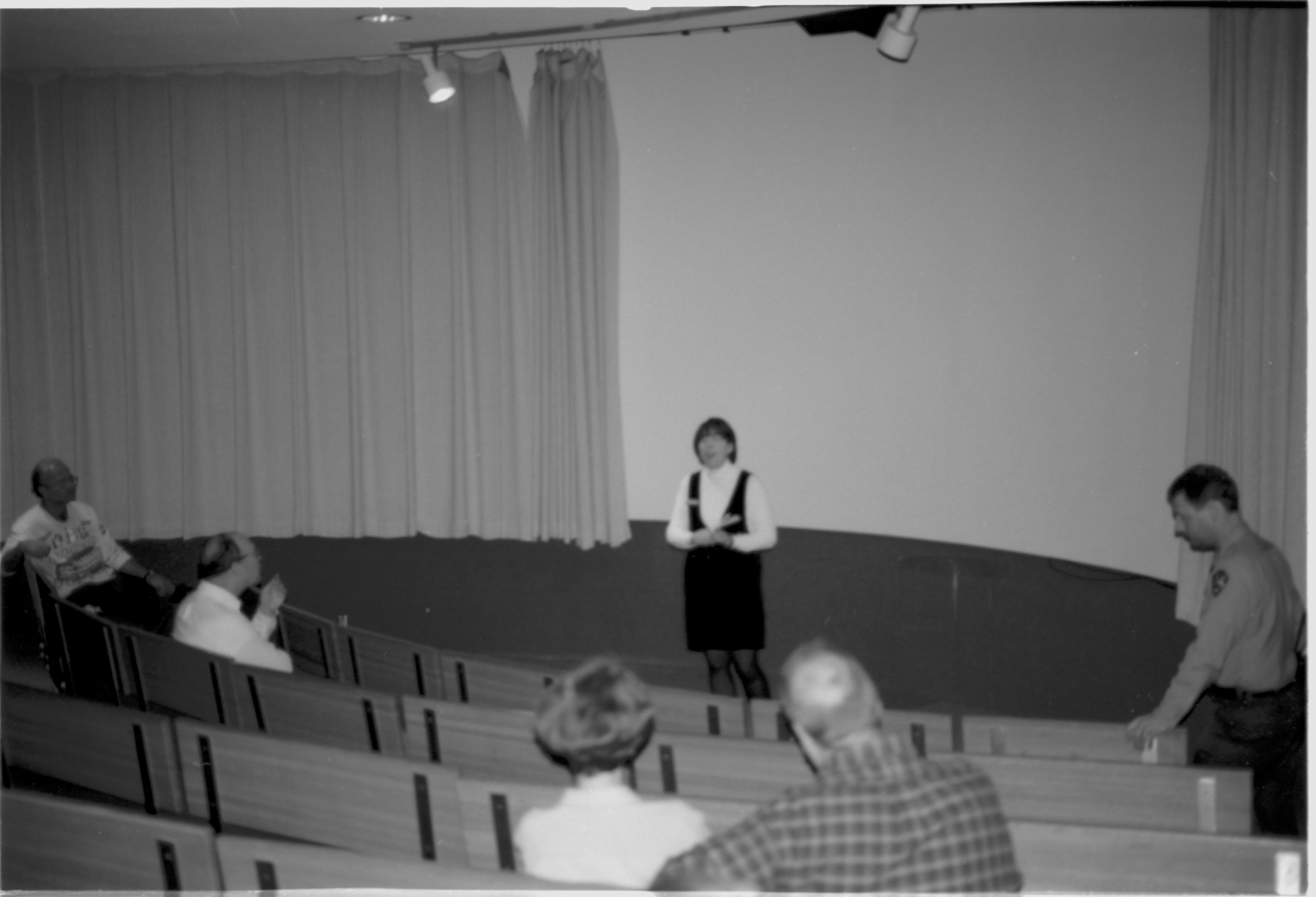 Lady speaking to visitors in theater. Lincoln Colloquium; UIS Roll#1, 4of4 Lincoln, Colloquium