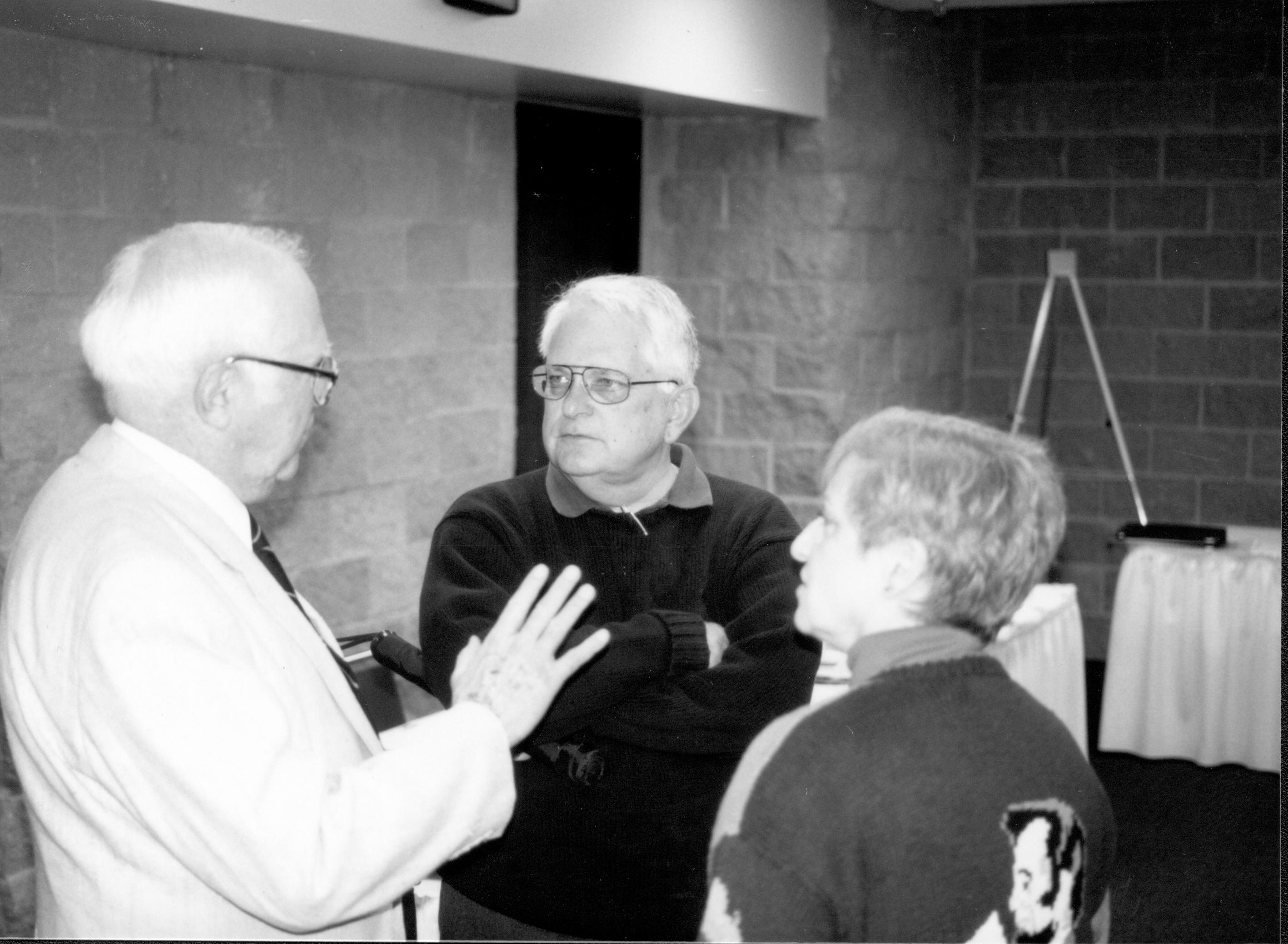 Man in light coat talking to two visitors. Lincoln Colloquium; UIS Roll#2, 3of4 Lincoln, Colloquium