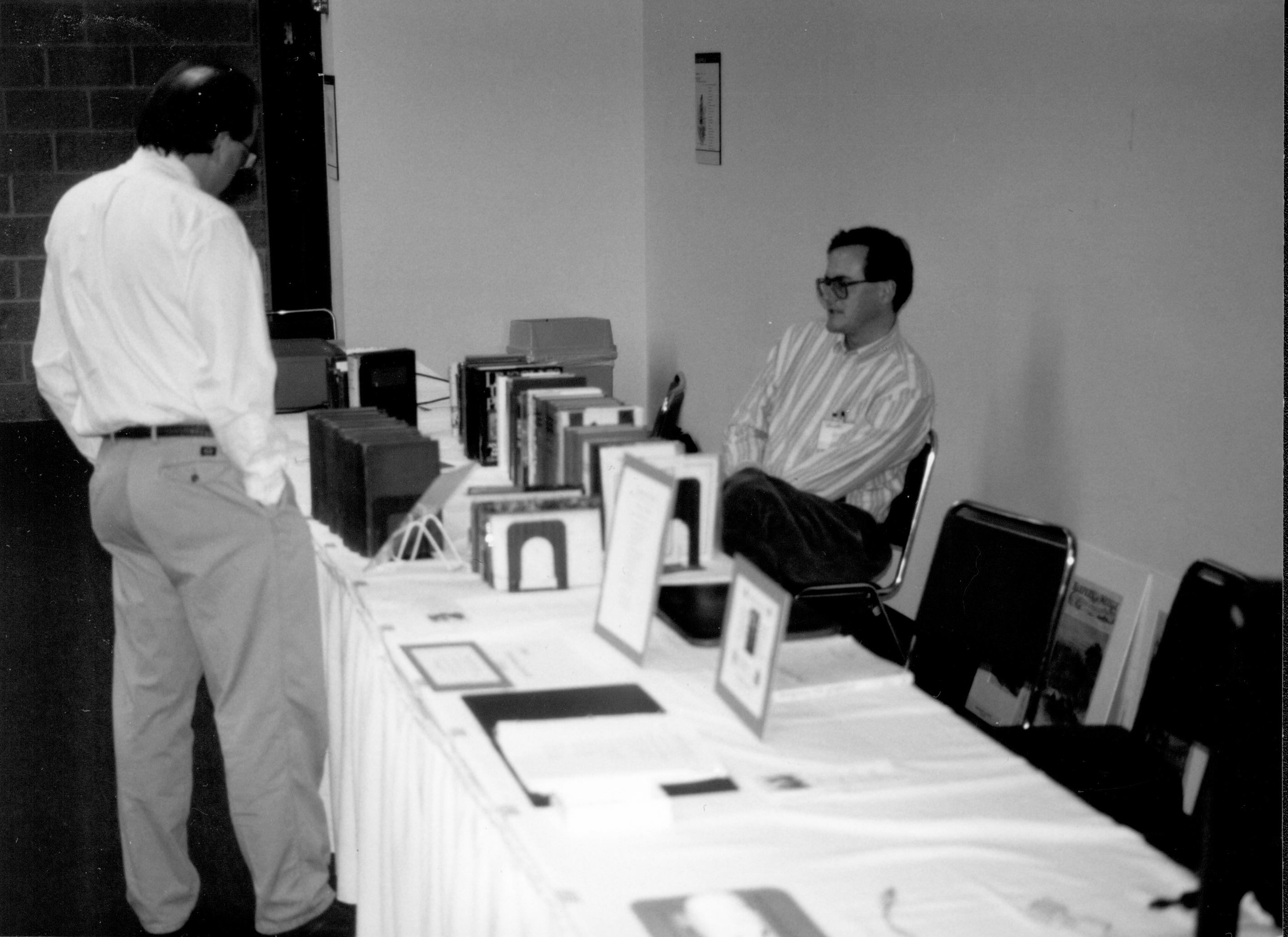 Man standing at book table, one seated. Lincoln Colloquium; UIS Roll#1, 1of4 Lincoln, Colloquium