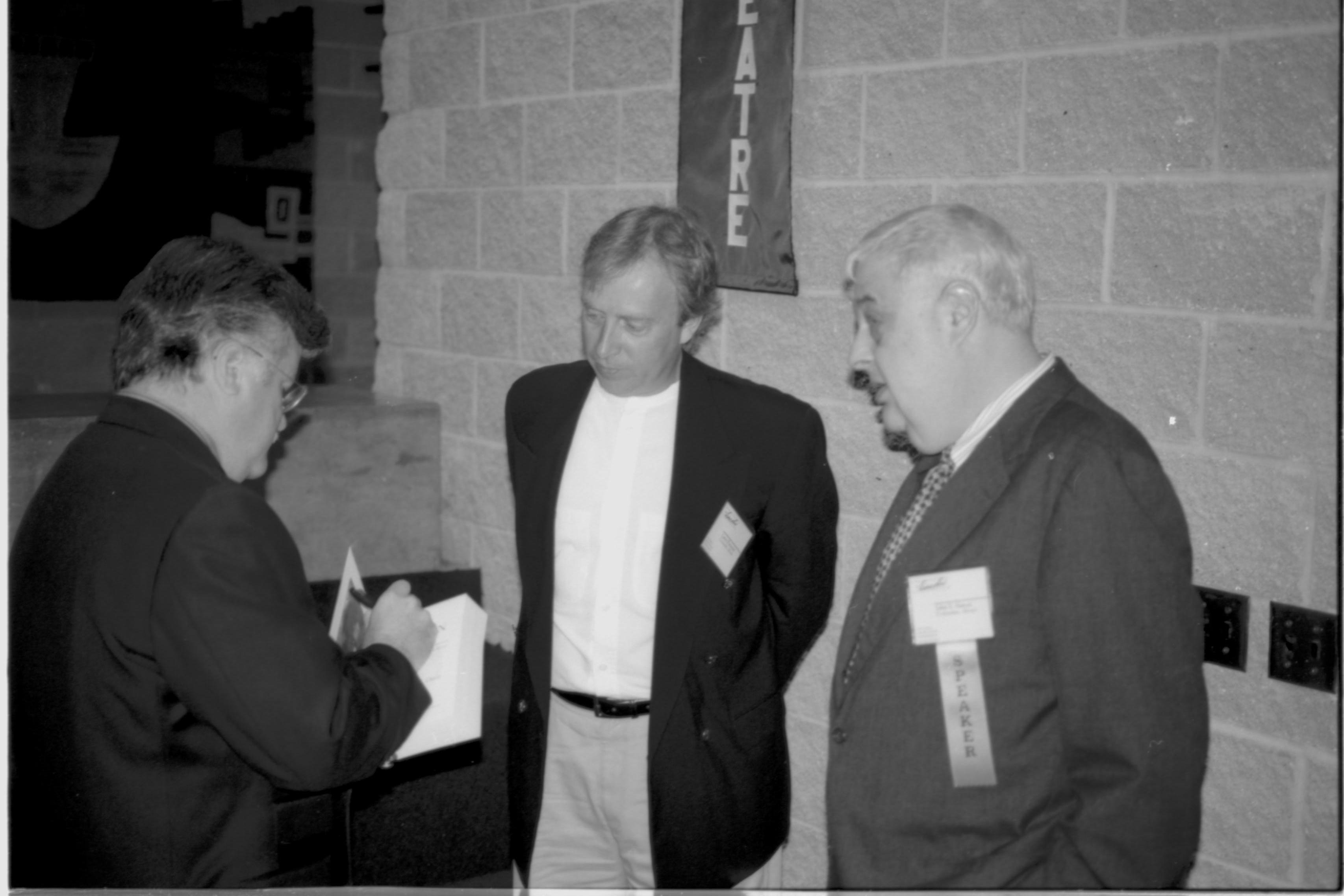 Two men watching a third sign a book. Lincoln Colloquium; UIS Roll#2, 4of4 Lincoln, Colloquium