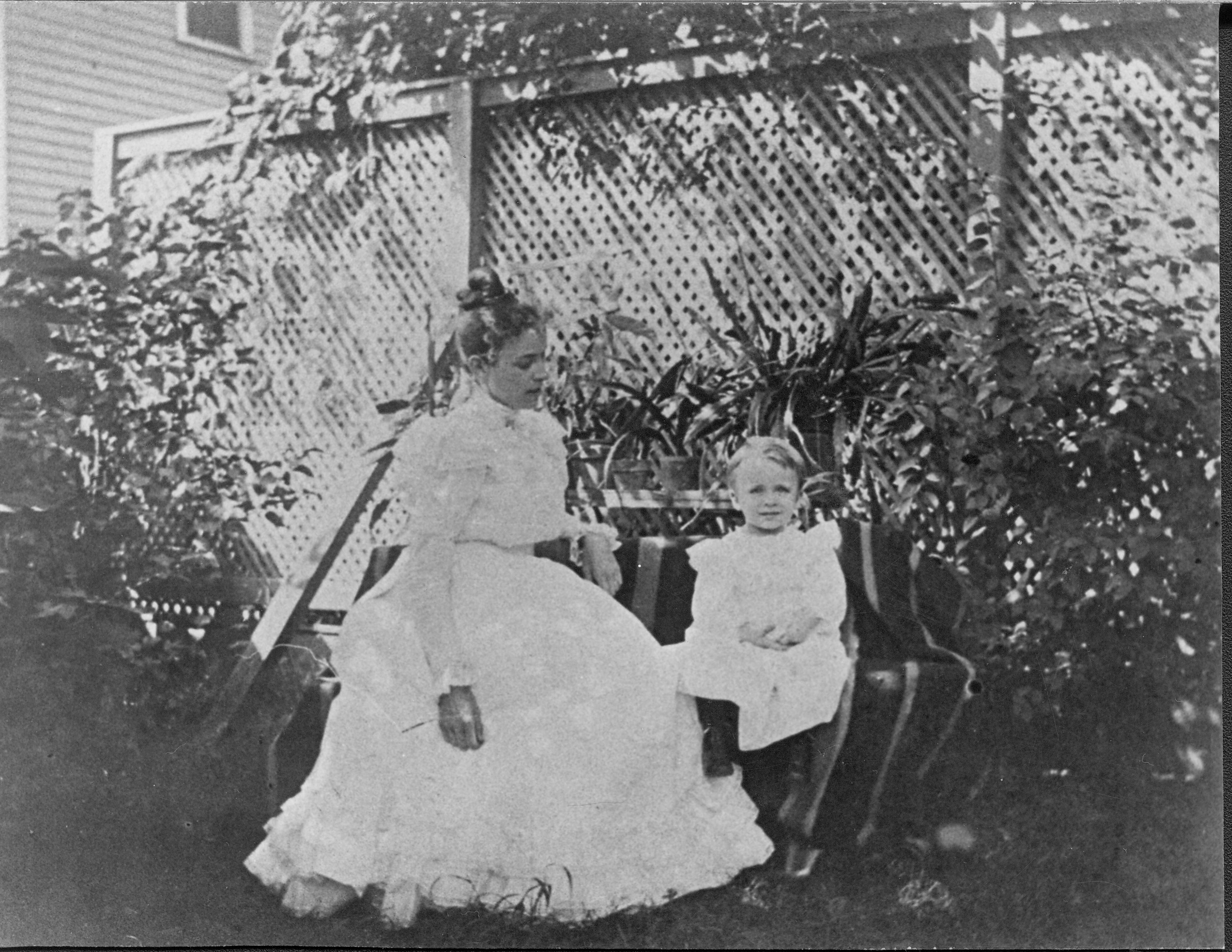 Margaret Robinson with Langdon (age 2) in side yard.  Henson Robinson Home in background. House visible is located to the north at 516 S. Eighth Street Portraits, Robinson