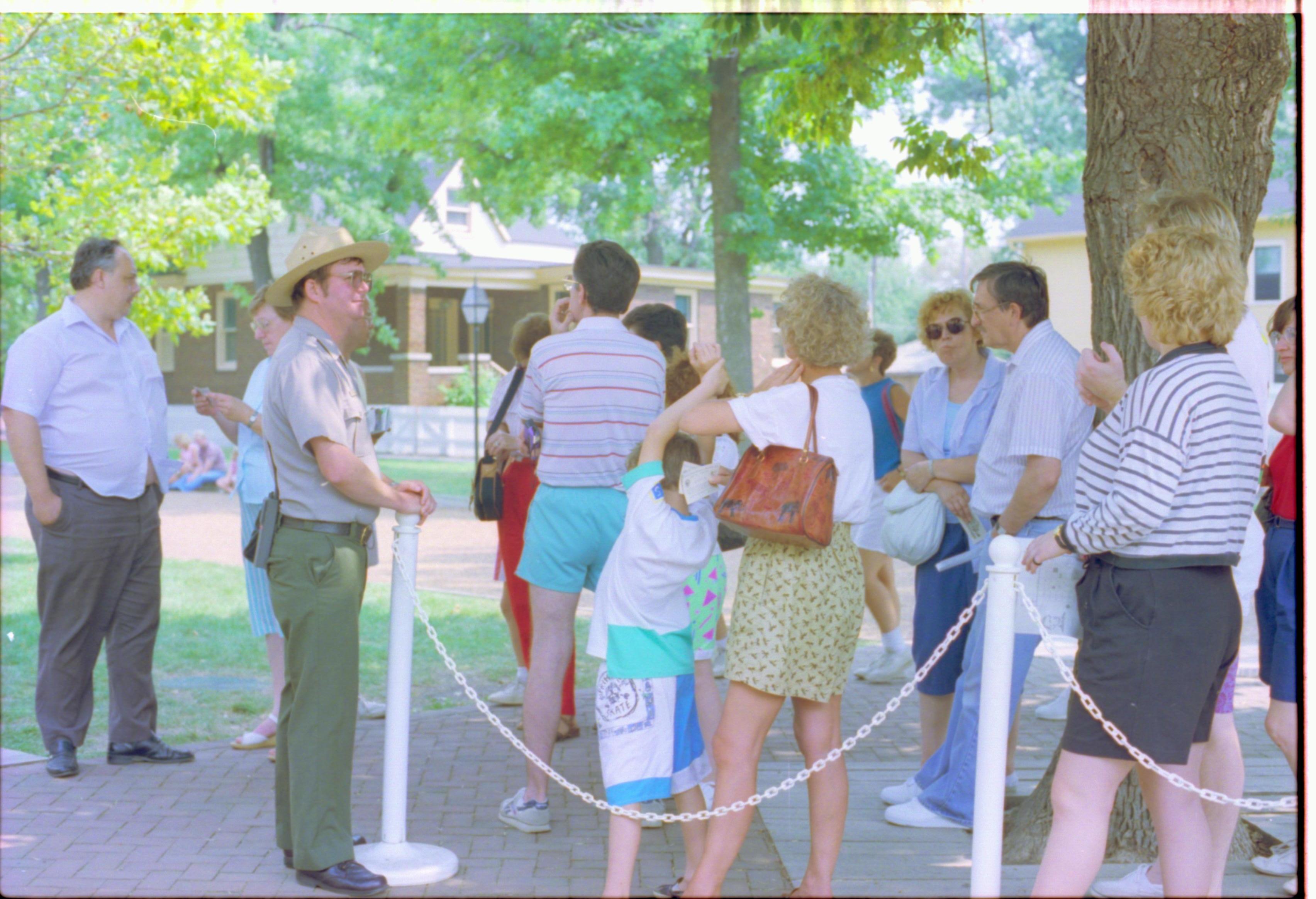 People standing behind white chain barrier. Interpretation
