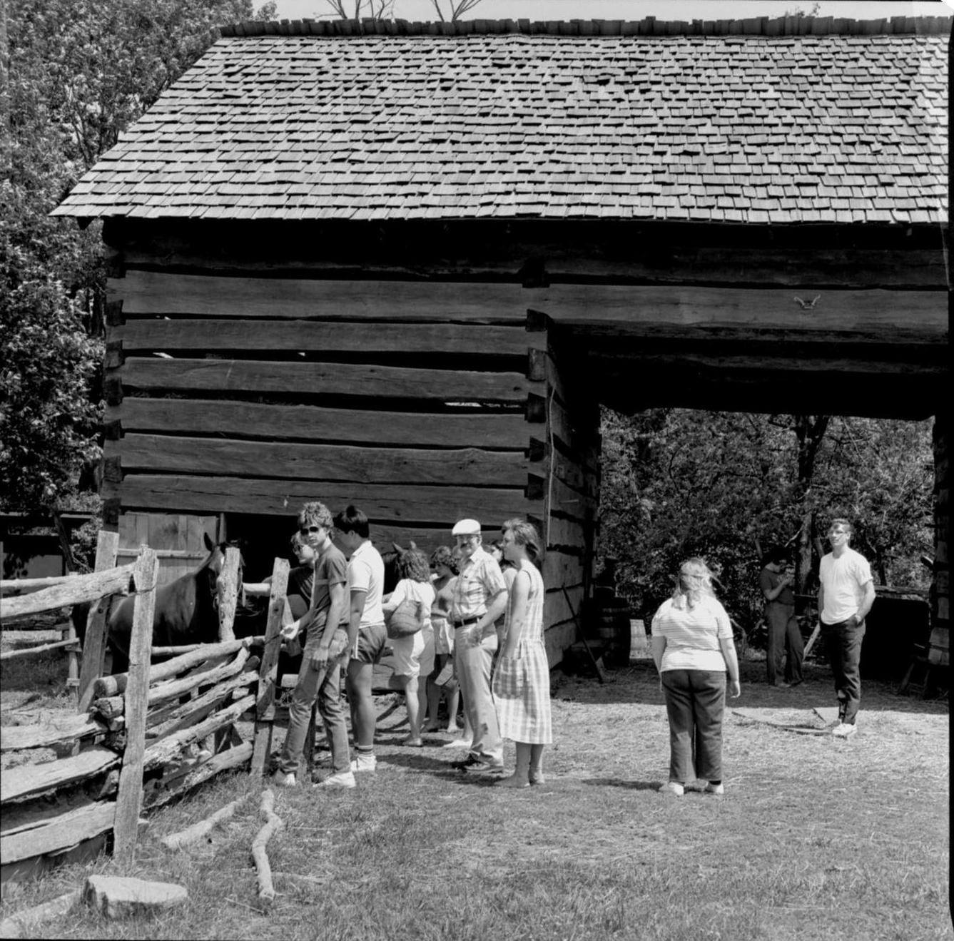 People standing outside barn. Log Cabin, State Park