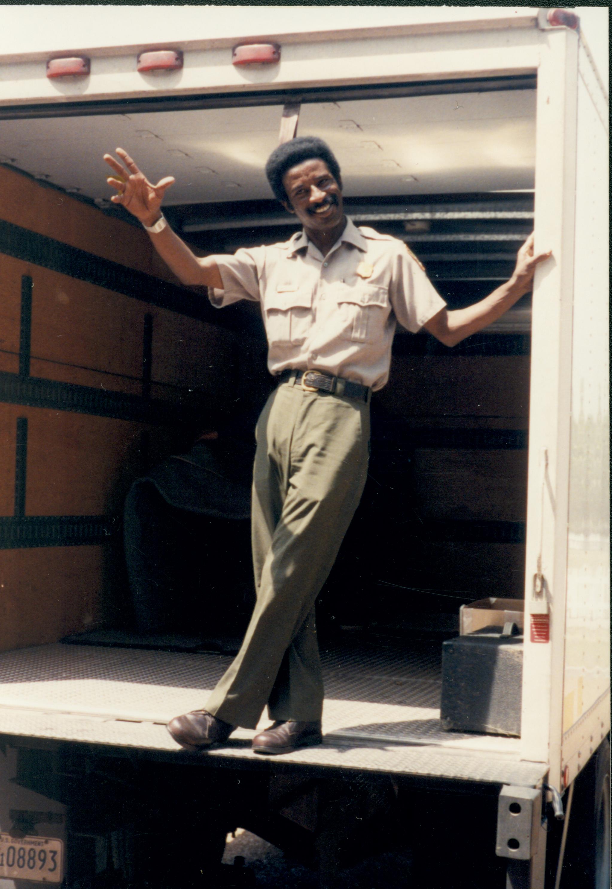 Ranger Melvin Cole waving while standing on a truck tailgate staff, truck