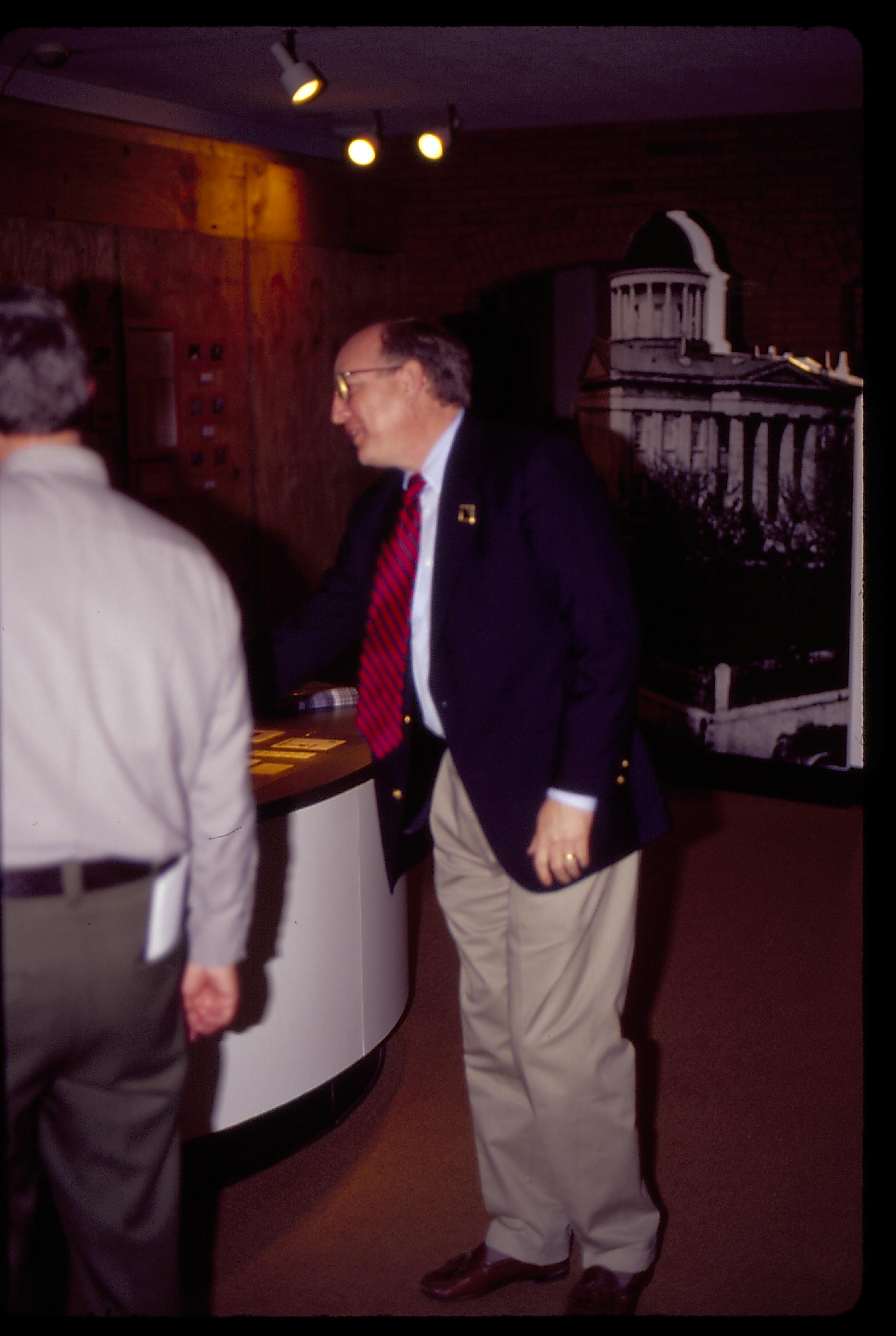 Farewell party for Dept. Supt. Larry Blake in Visitor Center. Larry looking at something on the desk with Supt. Norman Hellmers.  Construction wall in background (plywood)  Looking Northeast in lobby staff, Visitor Center, farewell