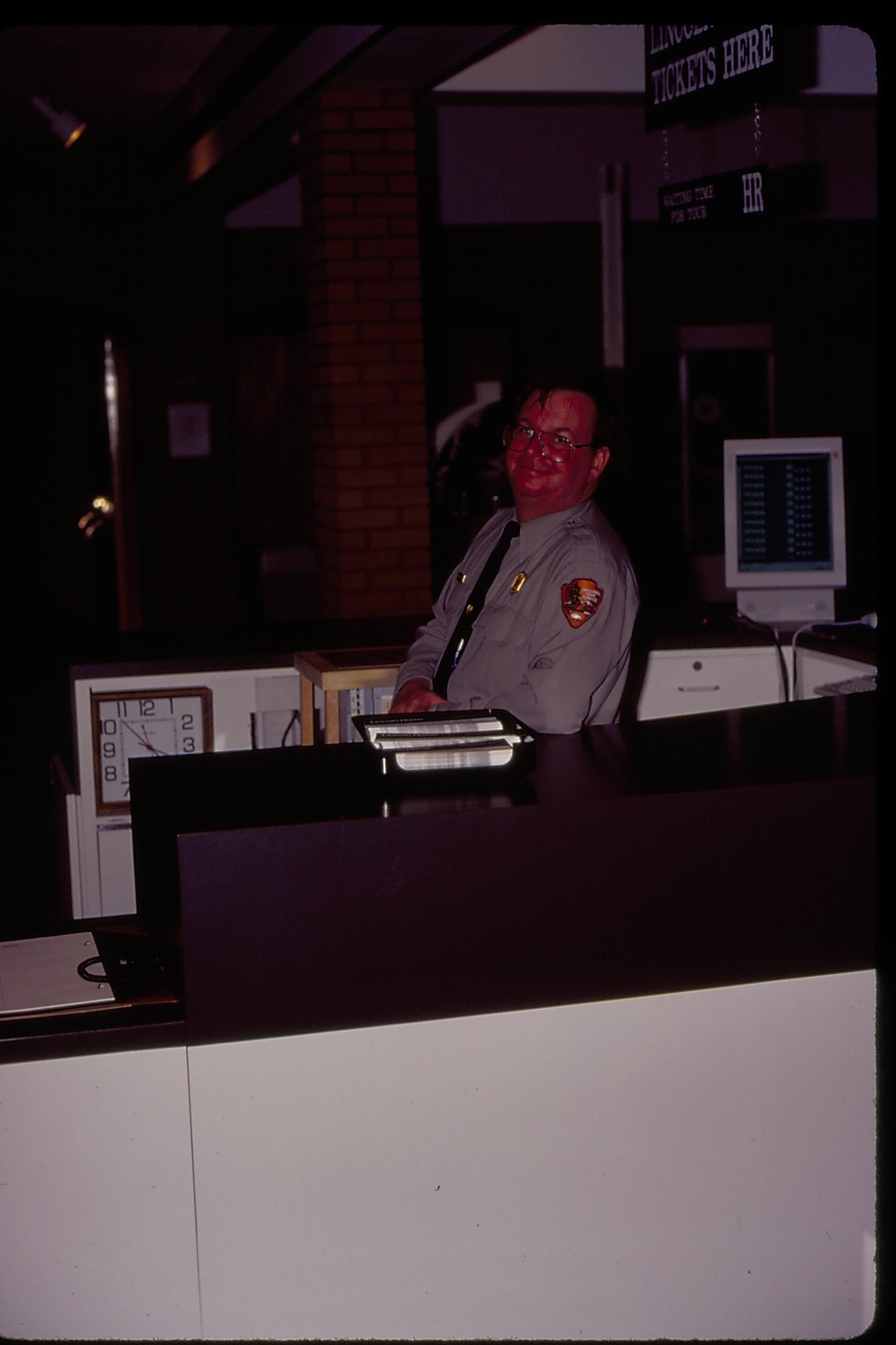 Farewell party for Dept. Supt. Larry Blake: Ranger Jim Ranslow at former boat front desk.  Some elements of the ticket system visible in background Looking Northwest (?) staff, Visitor Center, information desk, farewell