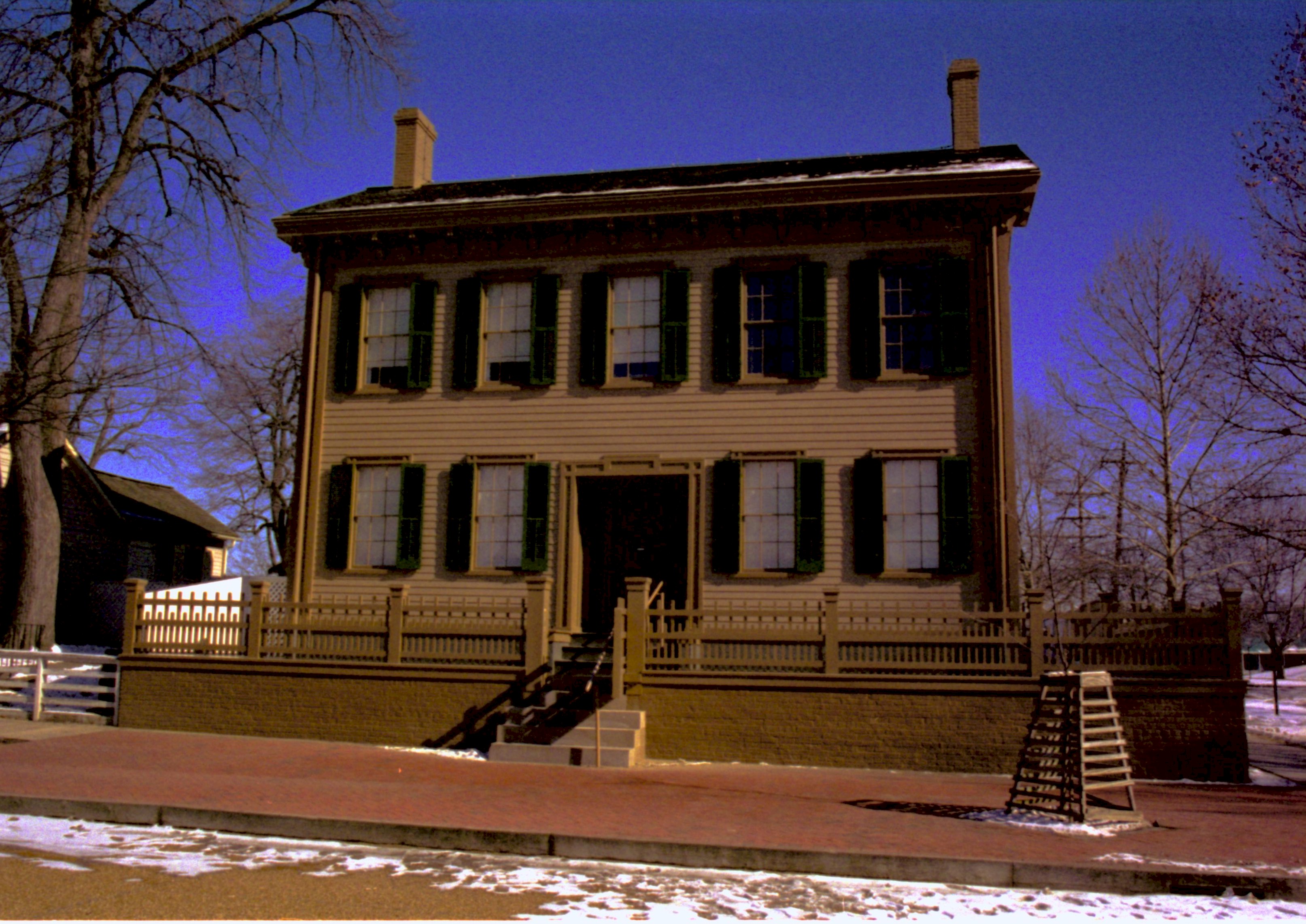 Lincoln Home in winter, some snow scattered throughout, cleared brick plaza in front, elm tree in cage on right. Corneau House on left in shadow Looking Northeast from 8th Street snow, Lincoln Home, Corneau, brick plaza, elm tree, 8th Street