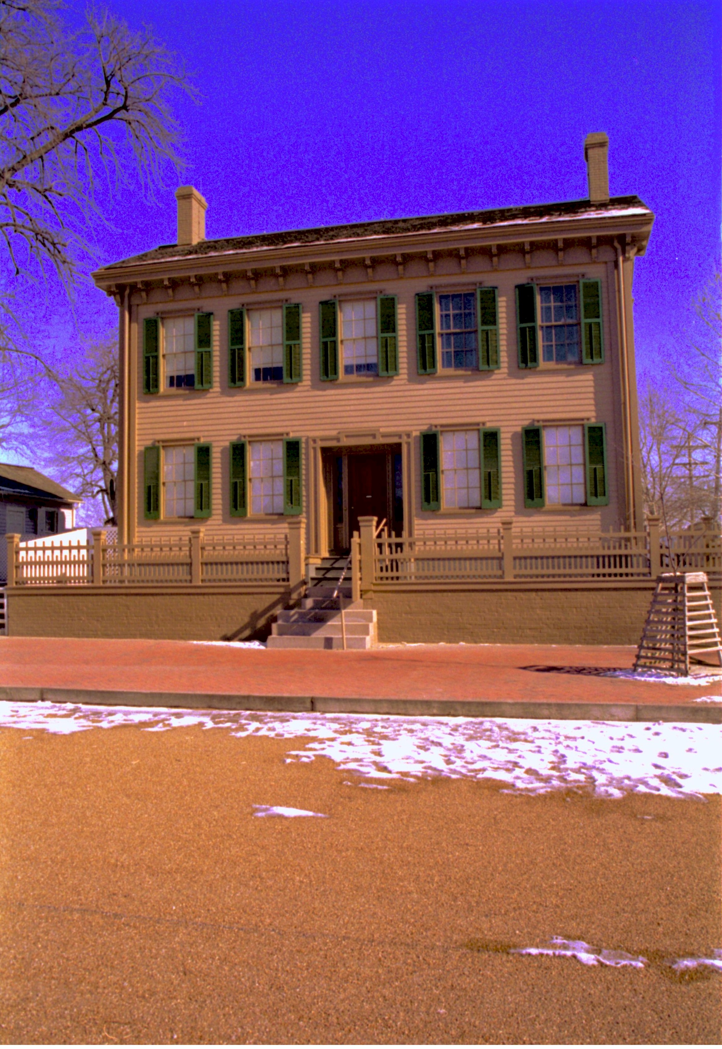 Lincoln Home in winter, snow visible.  Cleared brick plaza in front with elm tree in cage on right. Corneau House on left. Looking East/Northeast from 8th Street snow, Lincoln Home, brick plaza, elm tree, 8th Street, Corneau