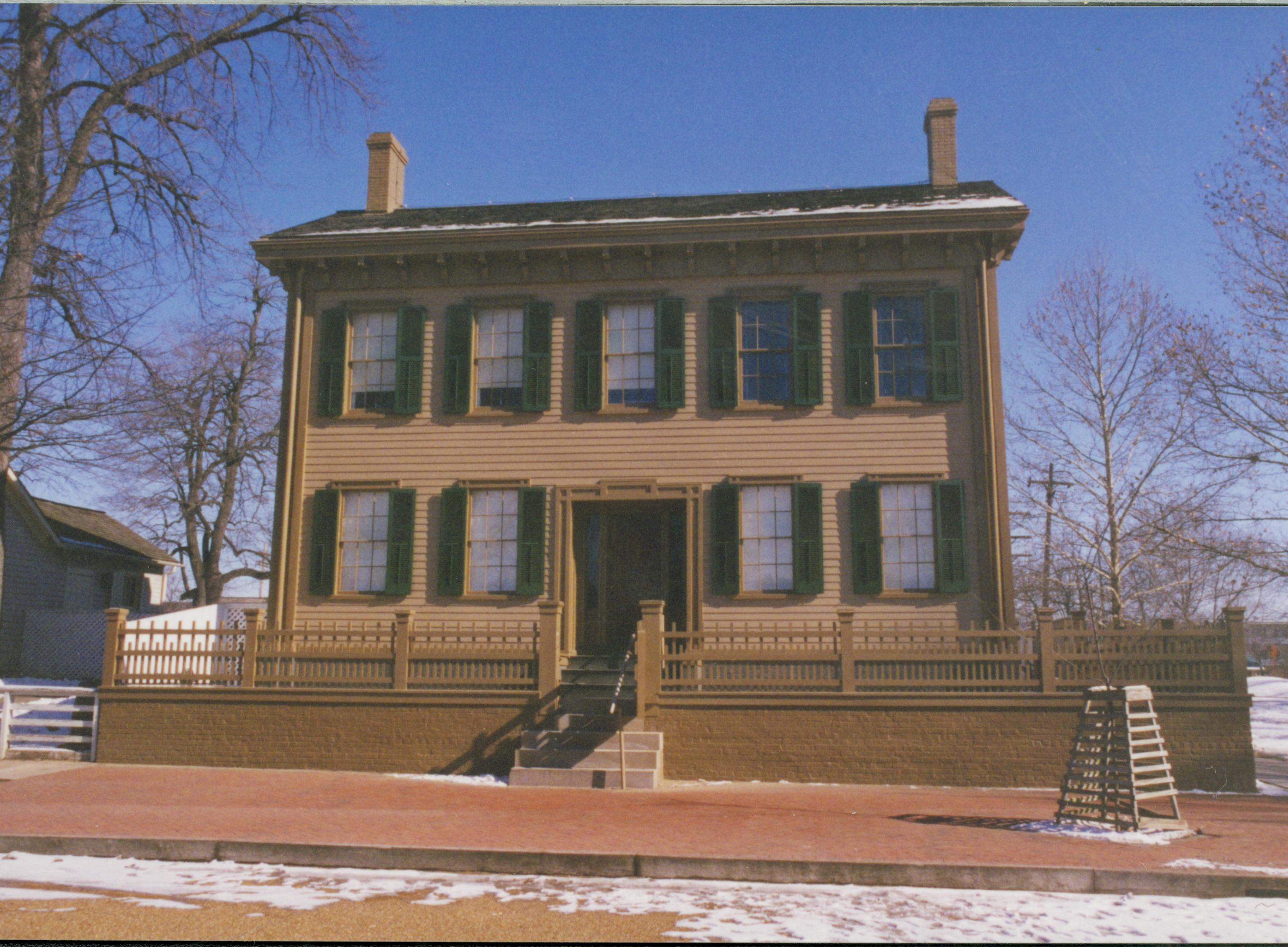 Lincoln Home in winter with some snow, cleared brick plaza in front, elm tree in cage on right. Corneau House on left. Looking East from 8th Street snow, Lincoln Home, 8th Street, Corneau, brick plaza, elm tree