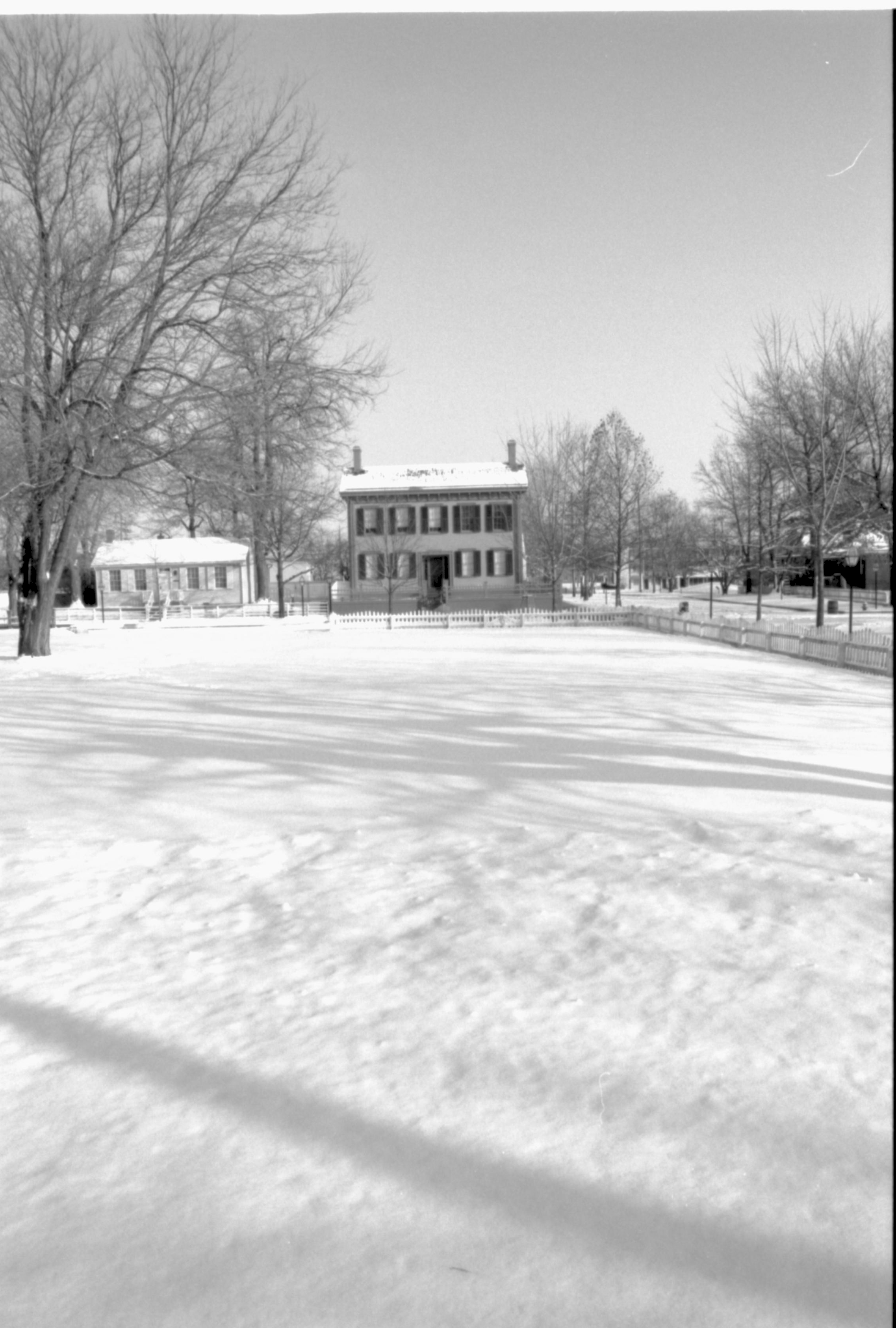 Lincoln neighborhood in snow.  Lincoln Home in center, Corneau House on left, Arnold House on right, Burch lot in foreground Looking East from alley behind Visitor Center over the Burch Lot, Block 7, Lot 9 snow, Lincoln Home, Corneau, Arnold, Burch Lot