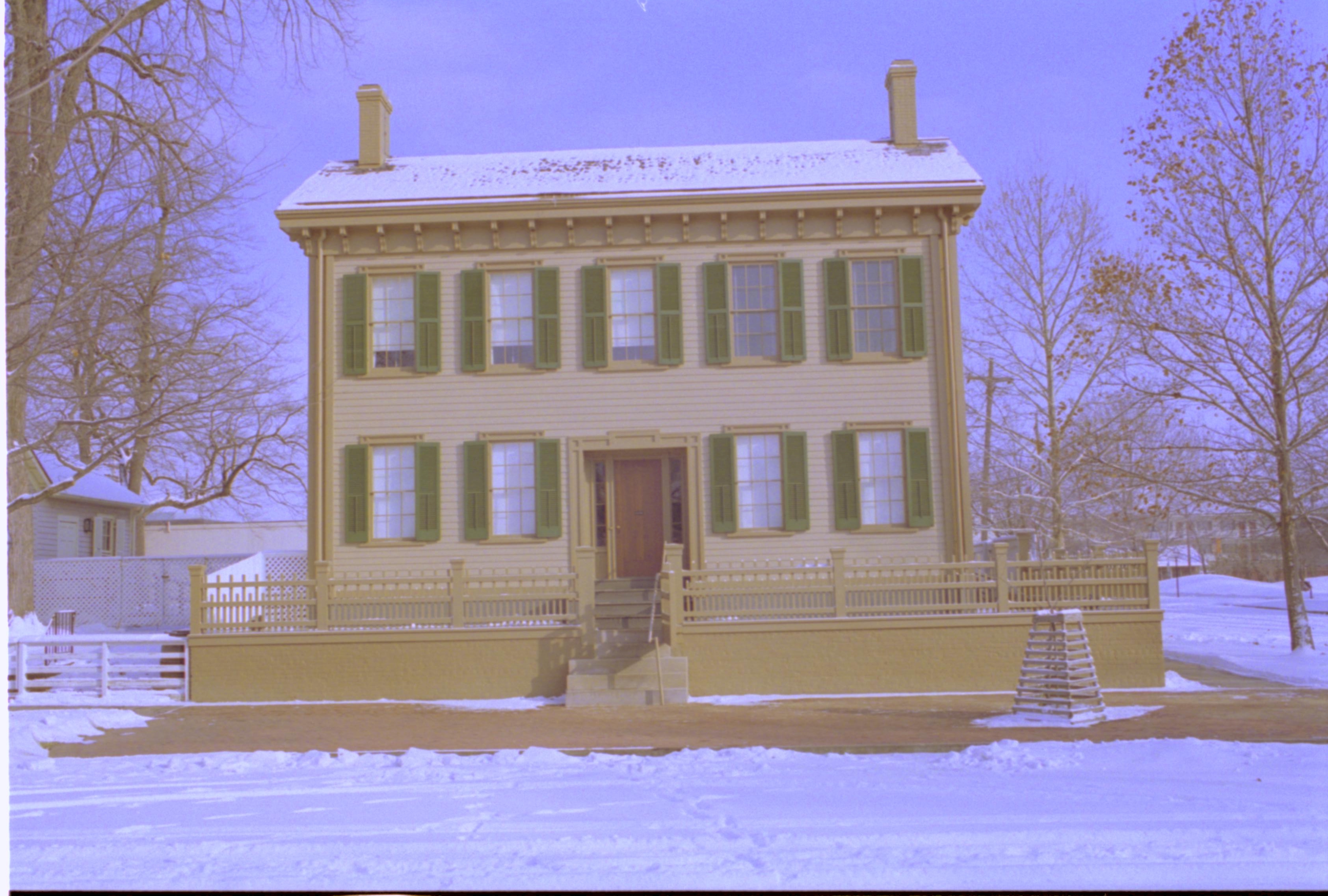 Lincoln Home in snow, cleared brick plaza in front, elm tree in cage on right. Corneau House on far left, B-2 in background left, former Travel Lodge Motel in background right Looking East from 8th Street snow, Lincoln Home, Corneau, Travel Lodge Motel, B-2