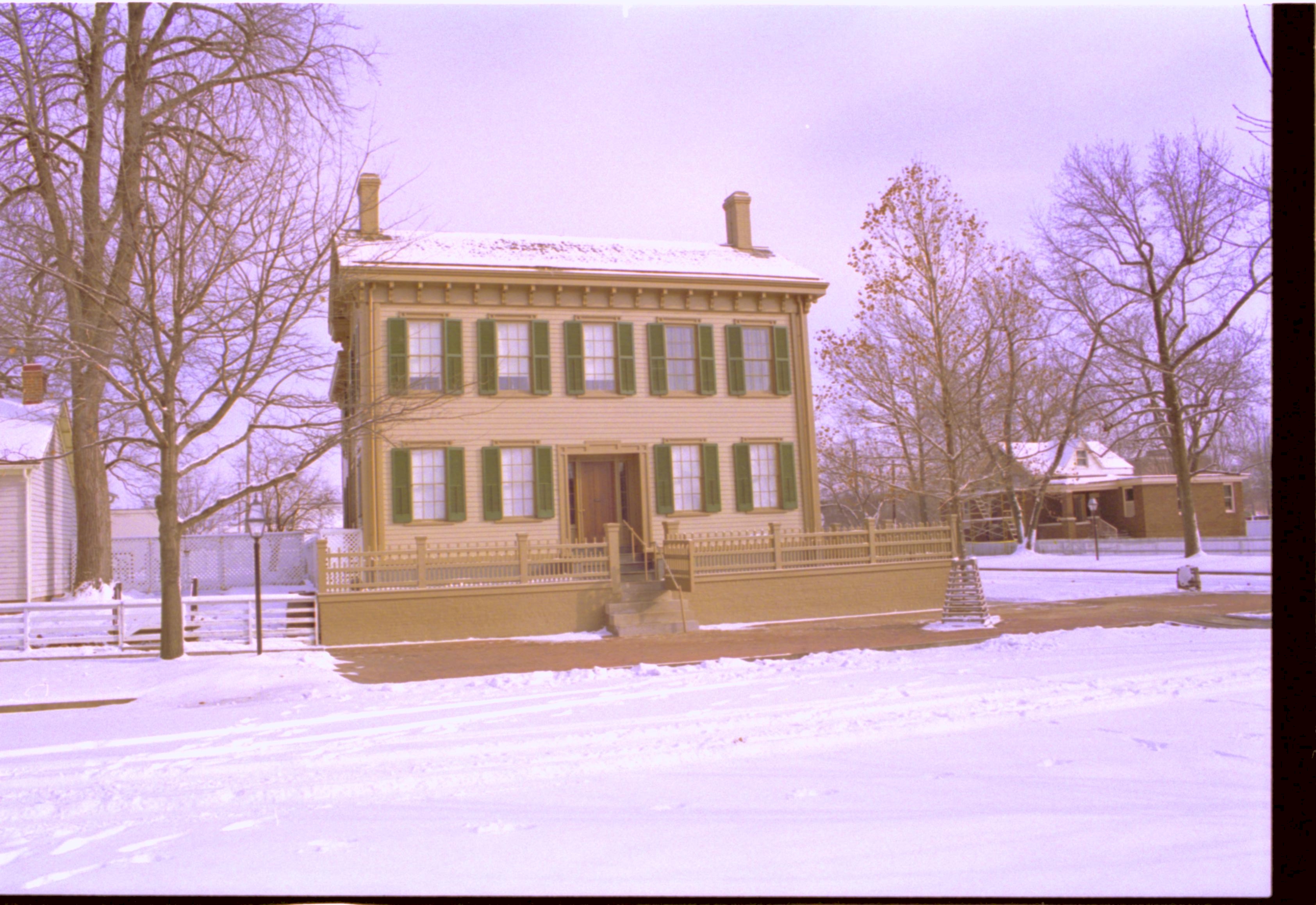 Lincoln Home in snow, cleared brick plaza in front, elm tree in cage on right. Corneau House on left, Arnold House in background right.  Looking East/Southeast from boardwalk west of 8th Street snow, Lincoln Home, Corneau, Arnold House, brick plaza, elm tree